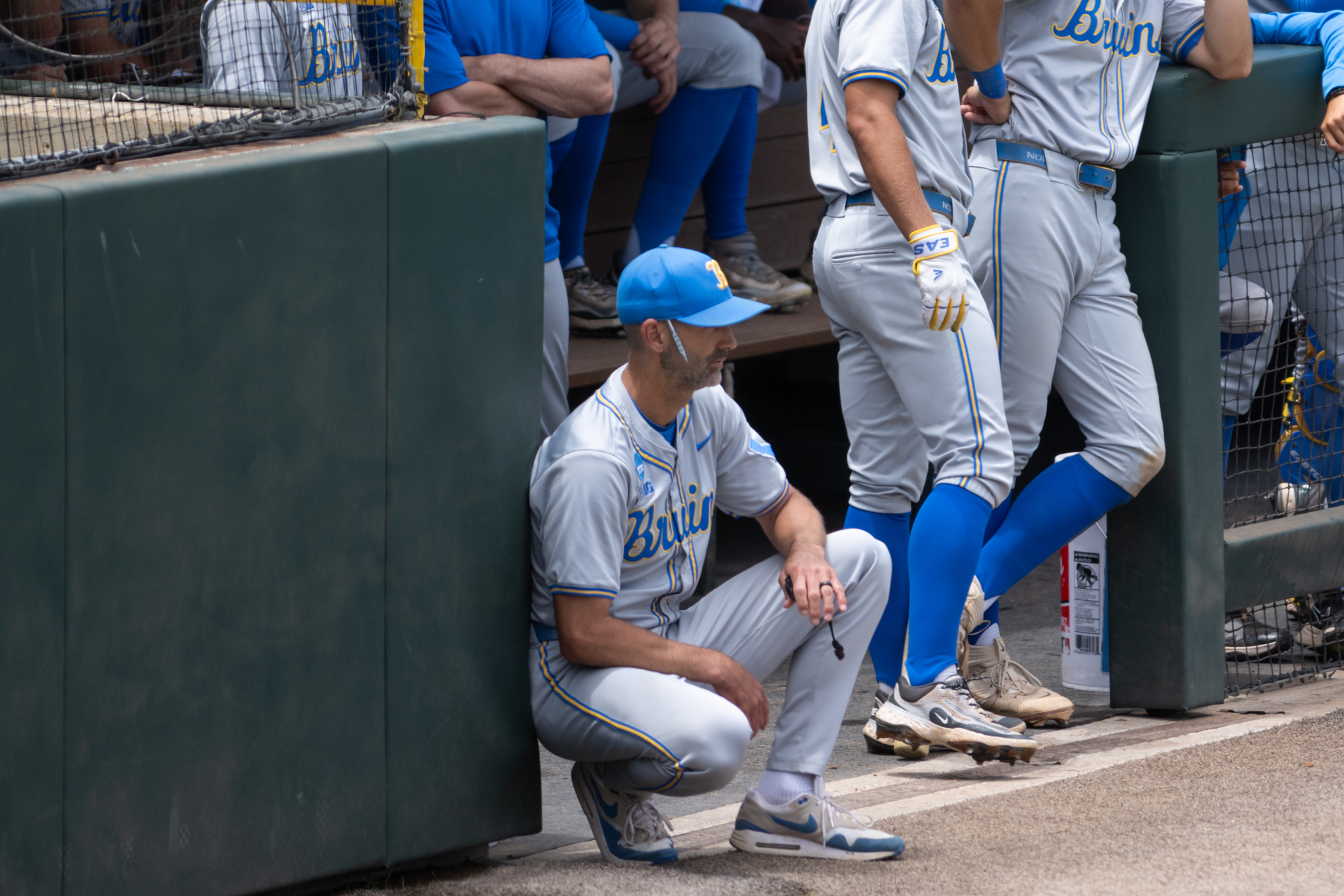 Assistant coach Bryant Ward squats at the dugout entrance. (Aidan Sun/Assistant Photo editor)