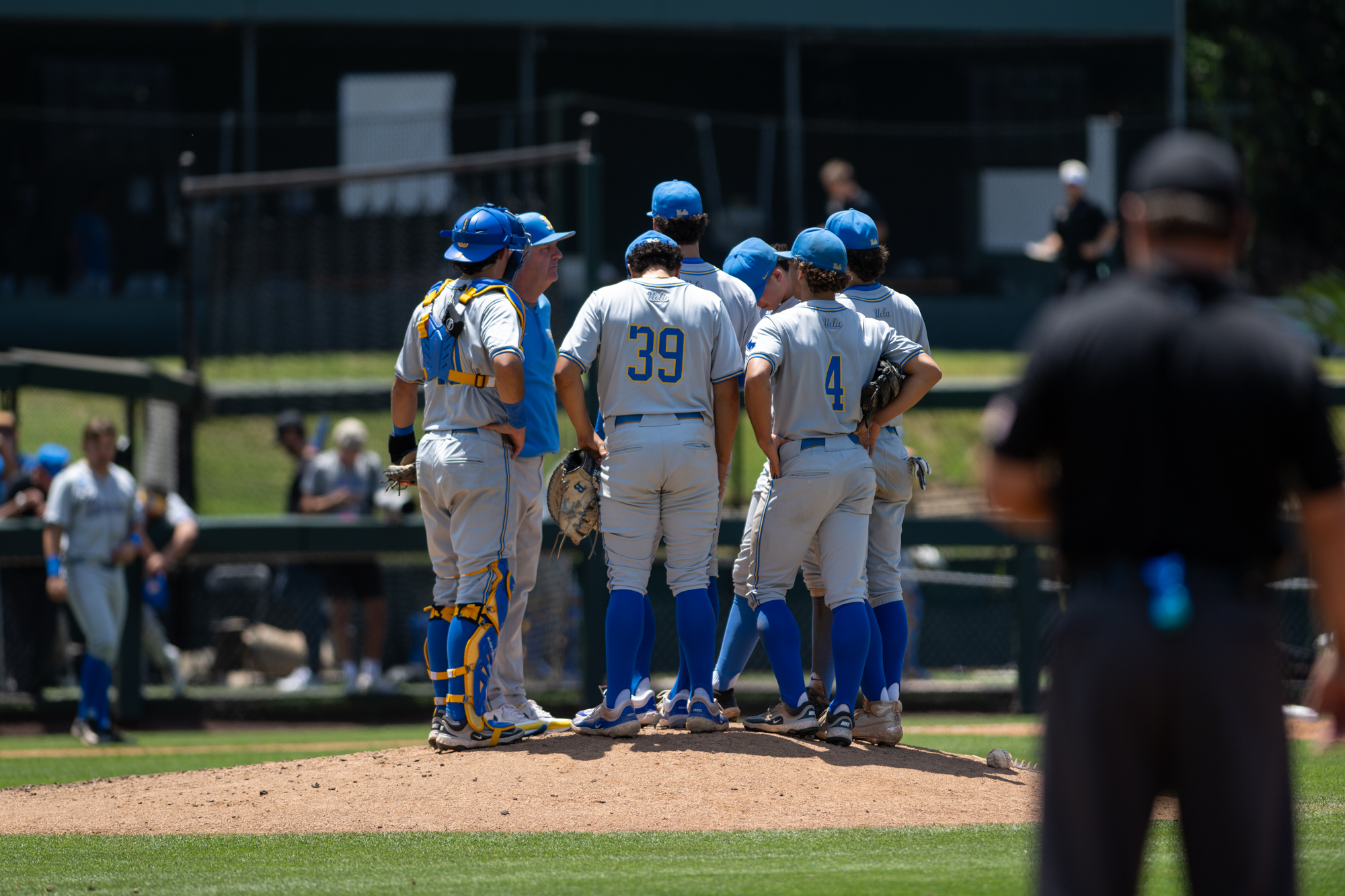 Coach John Savage and UCLA baseball's infield meet the pitcher on the mound. (Aidan Sun/Assistant Photo editor)