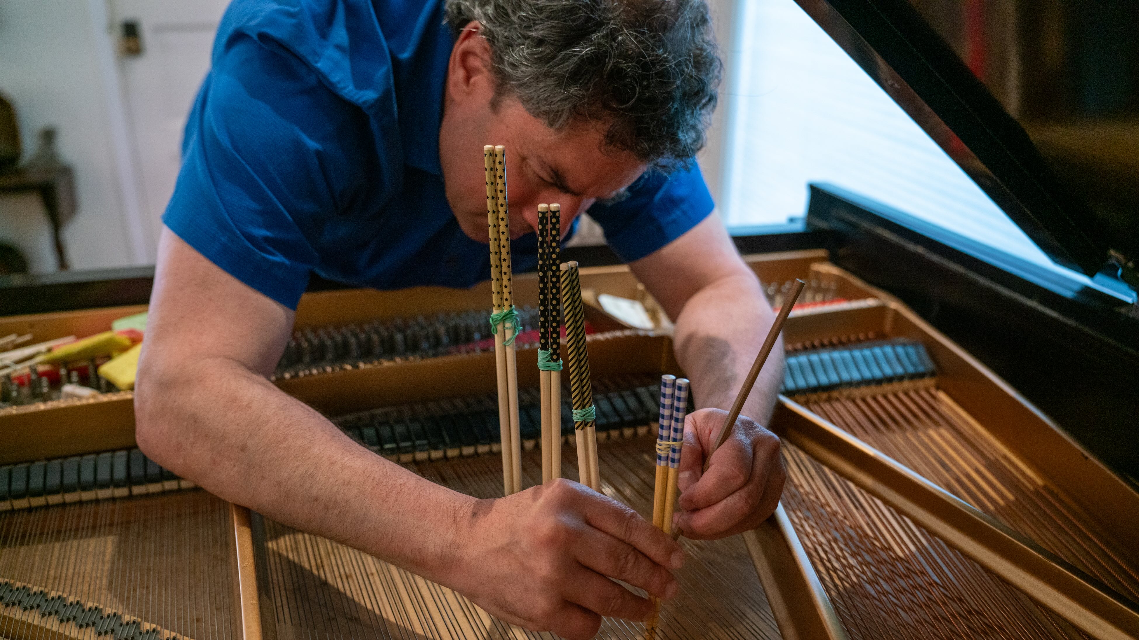 Pictured is David S. Lefkowitz arranging chopsticks into a piano's strings. The faculty composer experimented with multiple preparations in his new project to create unique sounds. (Courtesy of David S. Lefkowitz and Laura R. Lefkowitz)
