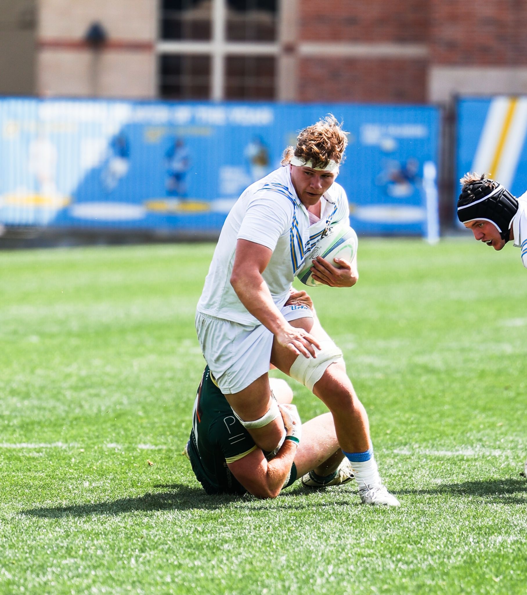 Sherman runs with the ball tucked under his arm as an opposing player attempts to drag him down by his leg.