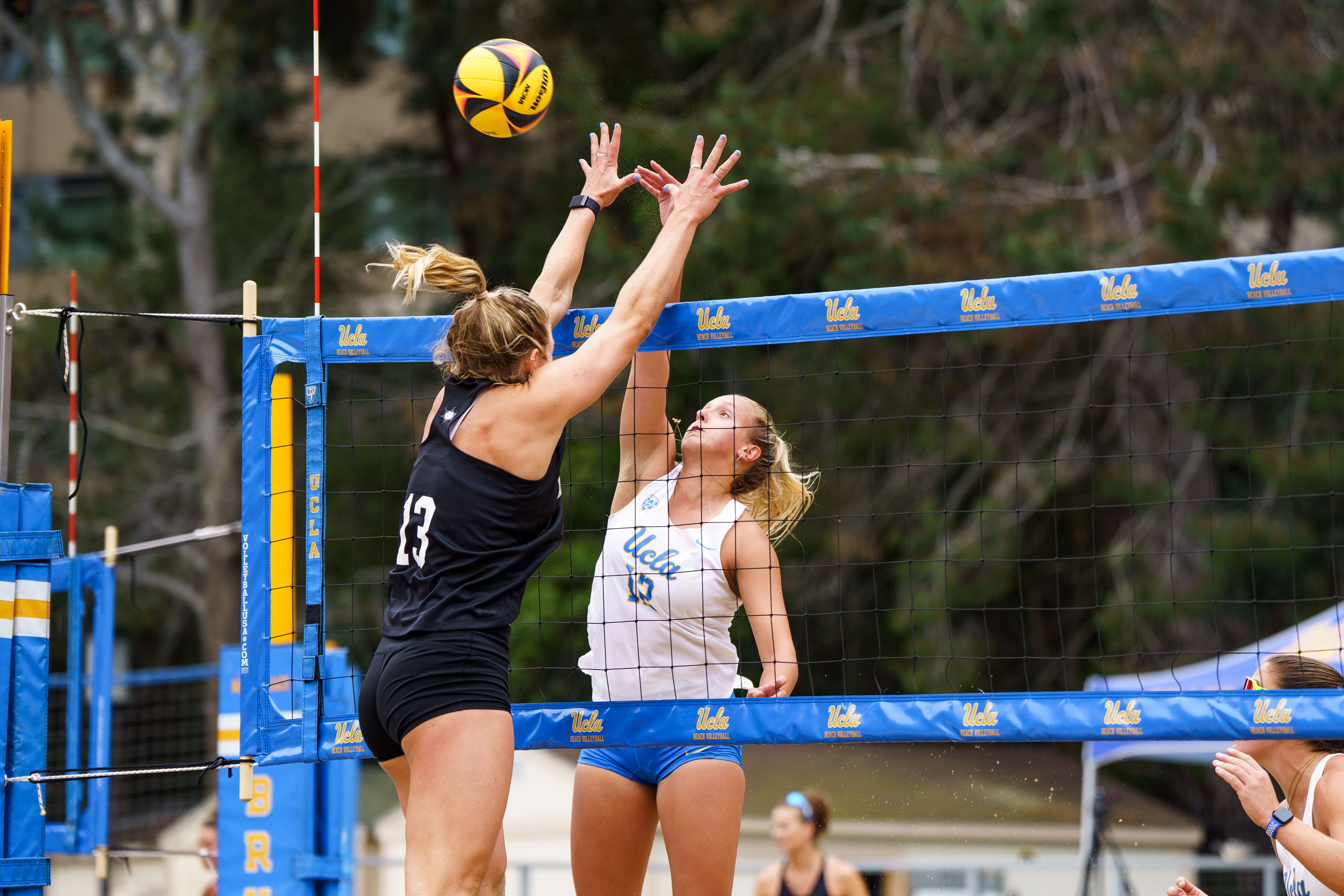 Senior defender Maggie Boyd jumps at the net and taps the ball above an opposing blocker's outstretched arms. Boyd earned the 2025 MPSF Player of the Year award and also captured the 2025 MPSF Pair of the Year award alongside sophomore blocker Sally Perez, who was Boyd's court partner last season.