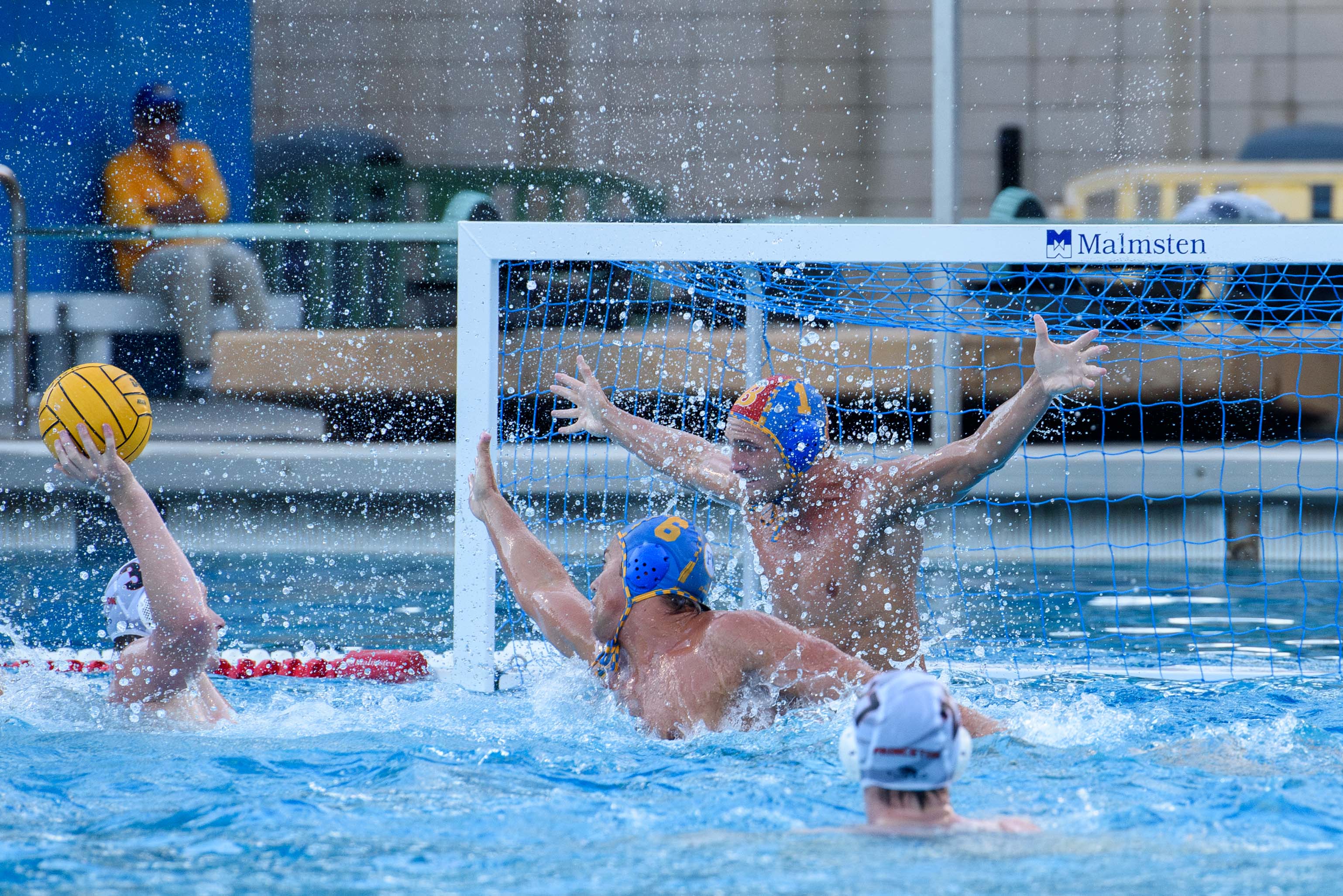 Redshirt sophomore goalkeeper Nate Tauscher raises both arms out of the water to attempt a block at an opposing shot. (Bettina Wu/Daily Bruin senior staff)
