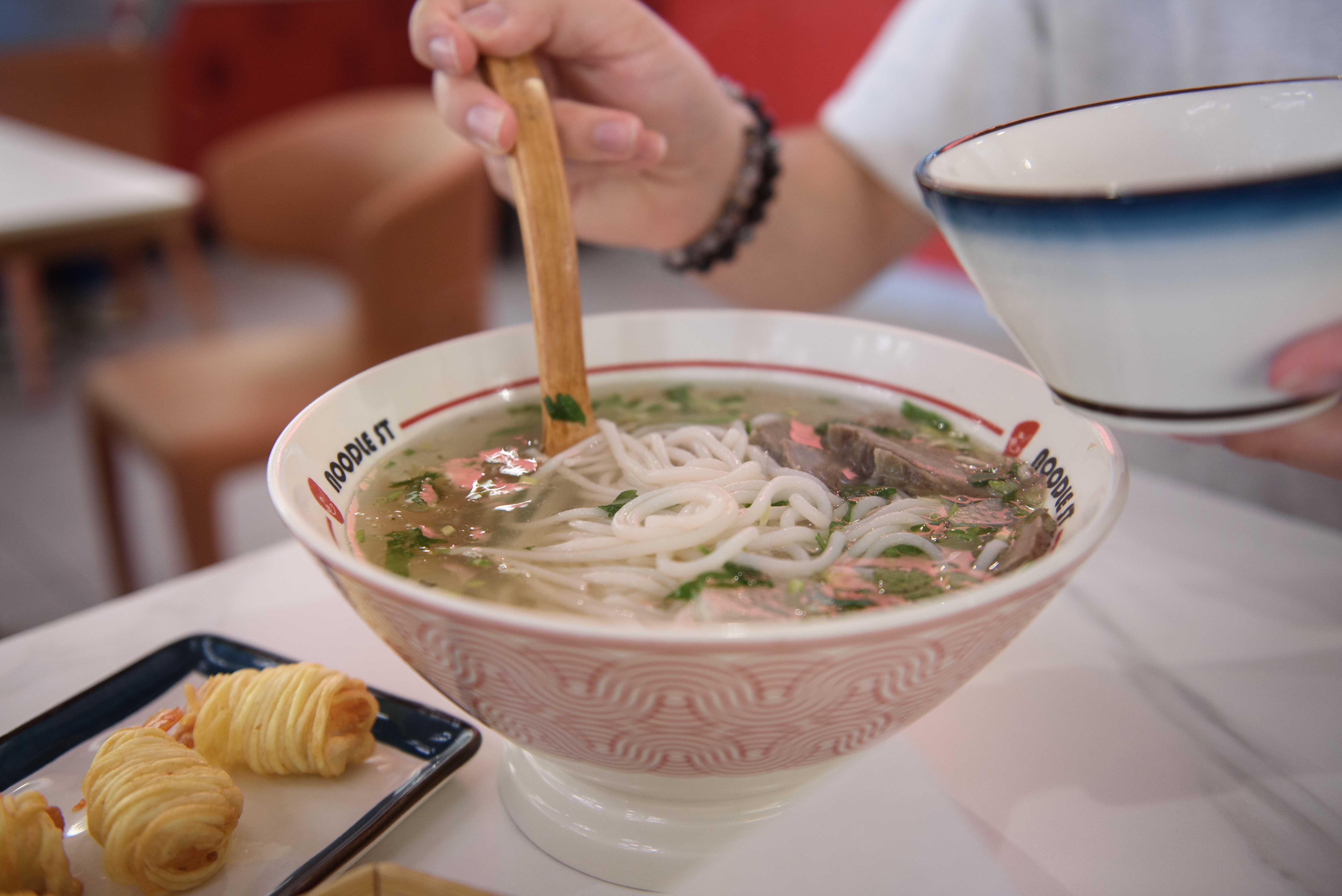 A restaurant-goer ladels out a portion from a bowl of the signature beef rice noodle soup. Sperisen writes that the restaurant maintained consistently high-quality service despite a lunch rush, and is fairly affordable for college students. (Leydi Cris Cobo Cordon/Daily Bruin senior staff)