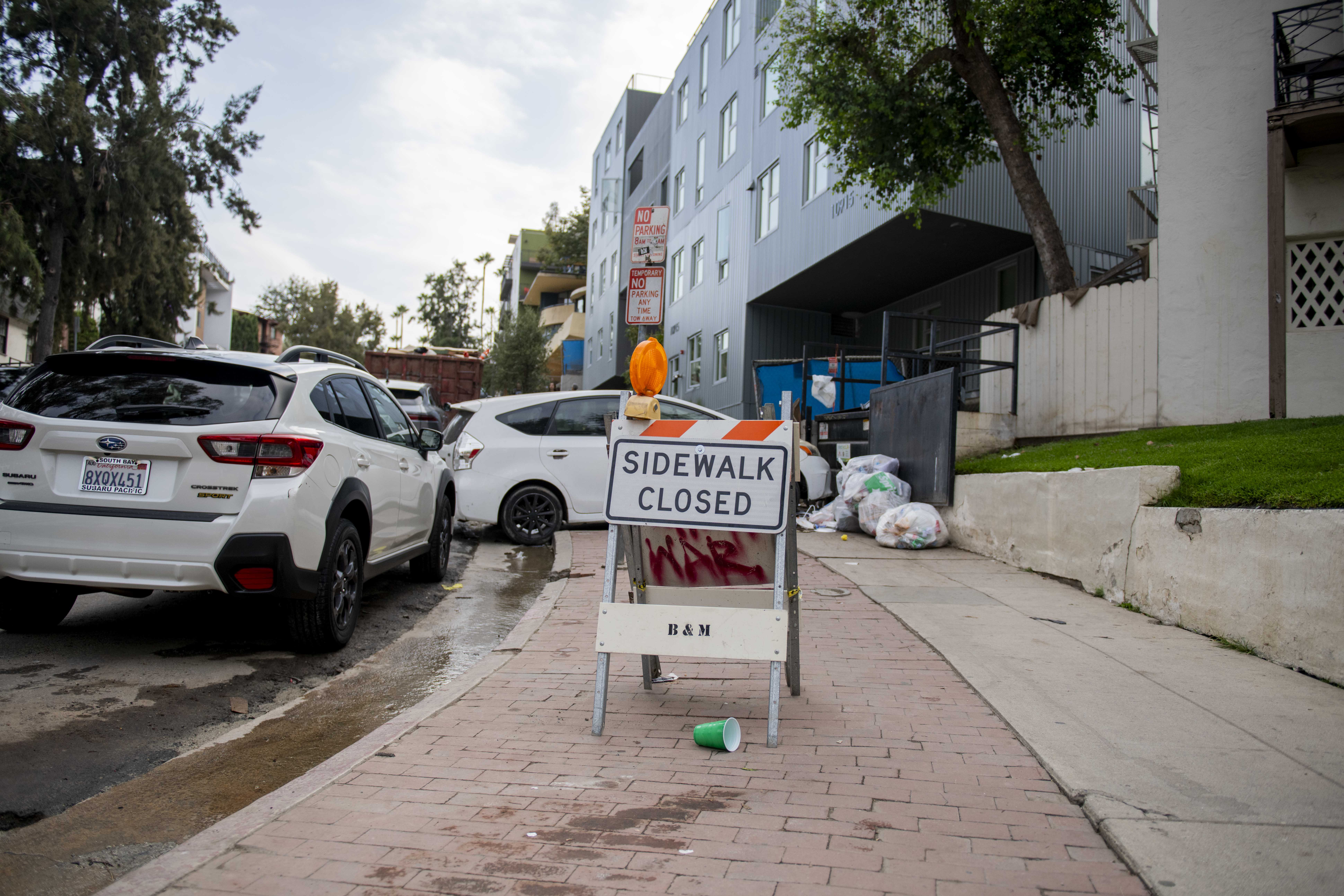 A sign reading "sidewalk closed" is pictured on Strathmore Drive. Blocked sidewalks near the intersection of Strathmore Drive and Gayley Avenue have led to pedestrians walking in the street. (Max Zhang/Daily Bruin staff)