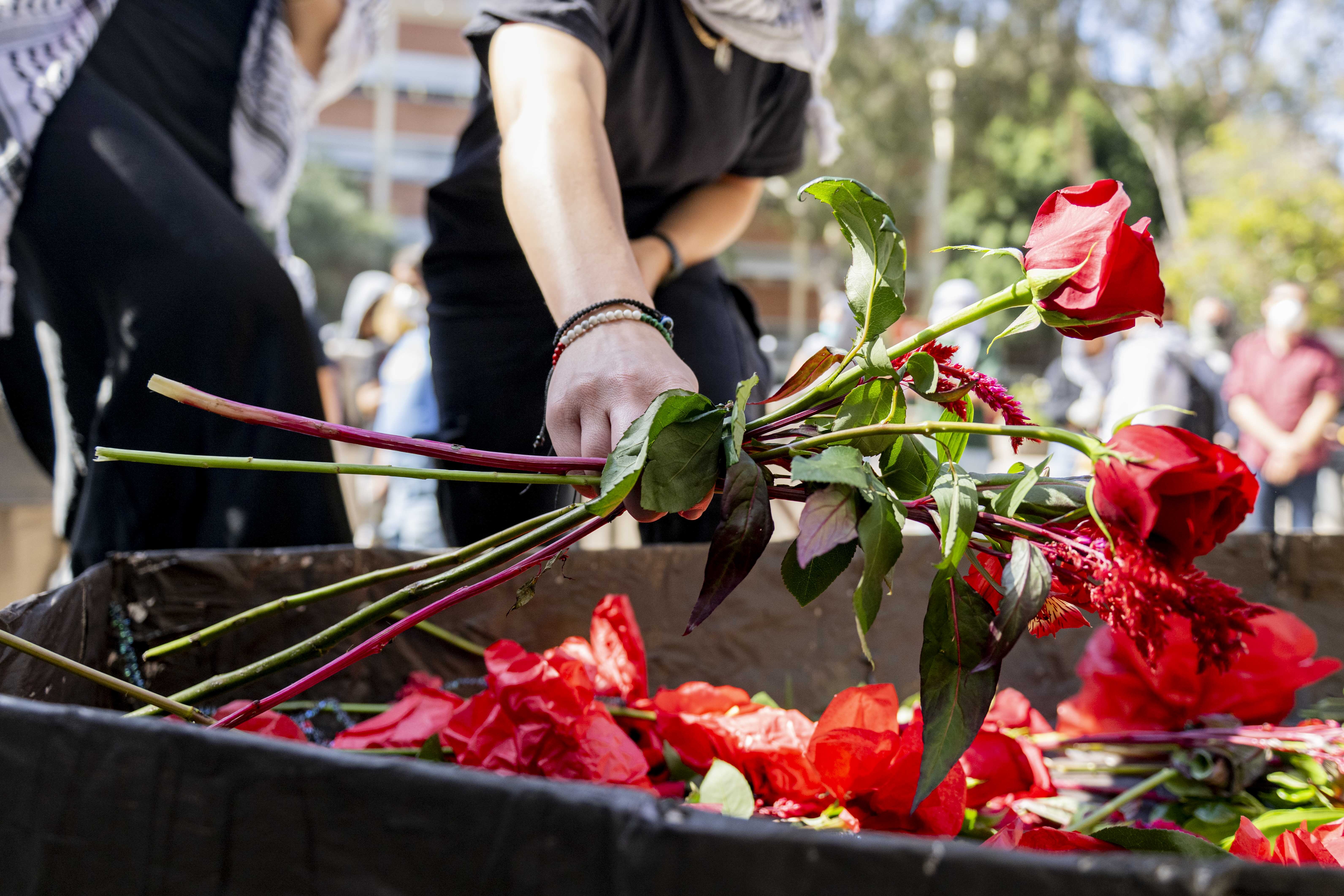 Protesters held Palestinian flags, carried a coffin-shaped object and pulled a wagon full of red flowers, which were then handed out to the group. (Andrew Ramiro Diaz/Photo editor)