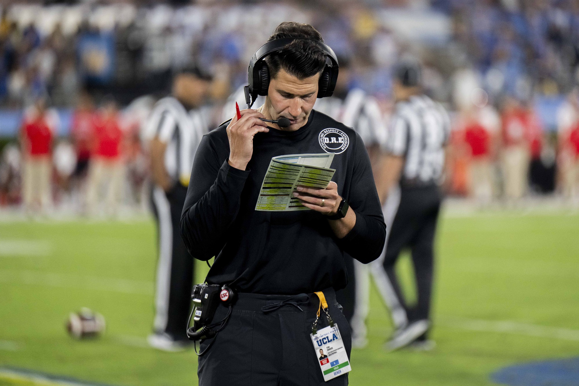 Former offensive coordinator and quarterbacks coach Tino Sunseri talks on the headset at the Rose Bowl. Sunseri mutually parted ways with UCLA on Tuesday. (Aidan Sun/Assistant Photo editor)