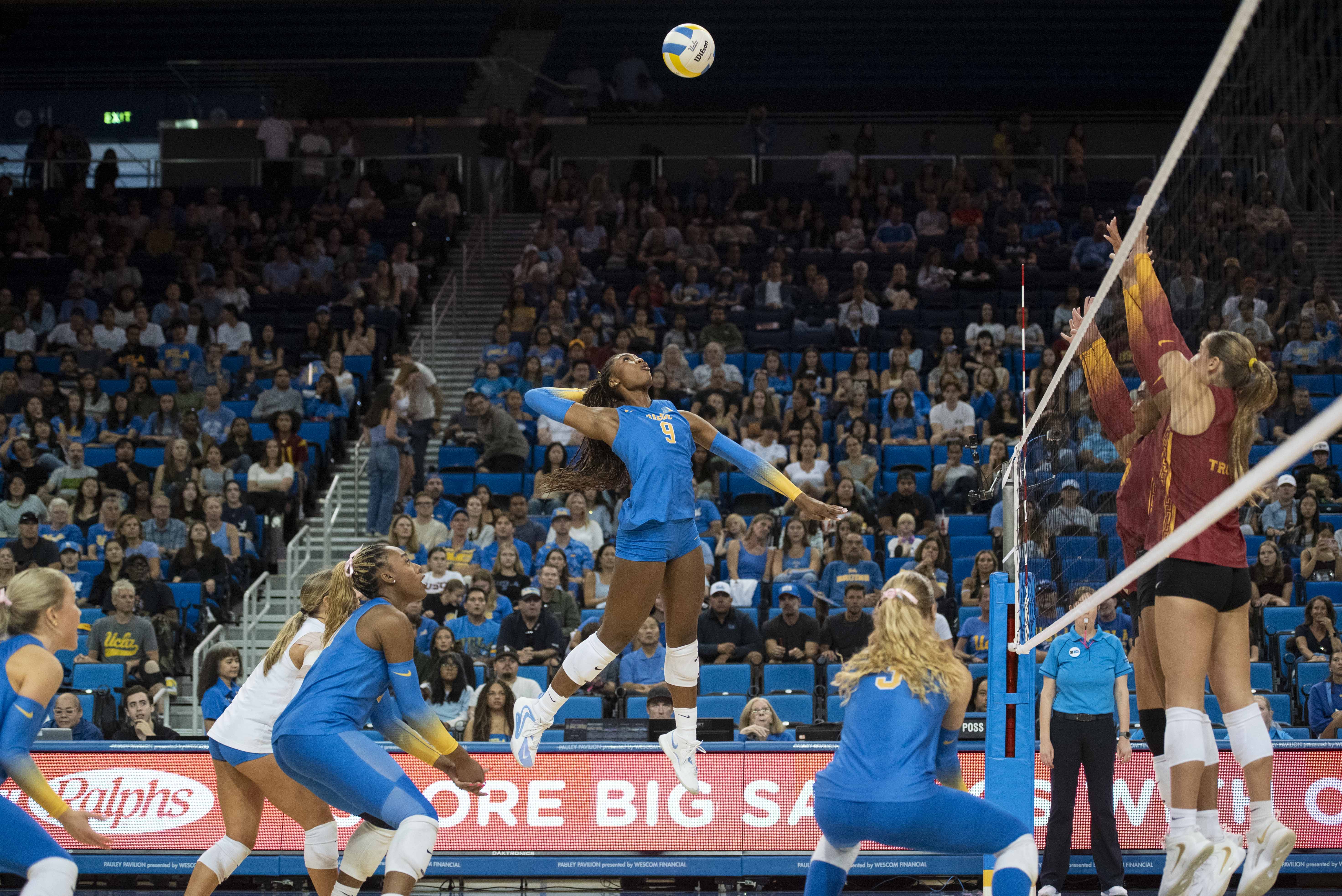 Senior outside hitter Cheridyn Leverette goes up for a swing over the Trojans block as her teammates get ready on defense. (Brianna Carlson/Daily Bruin staff)