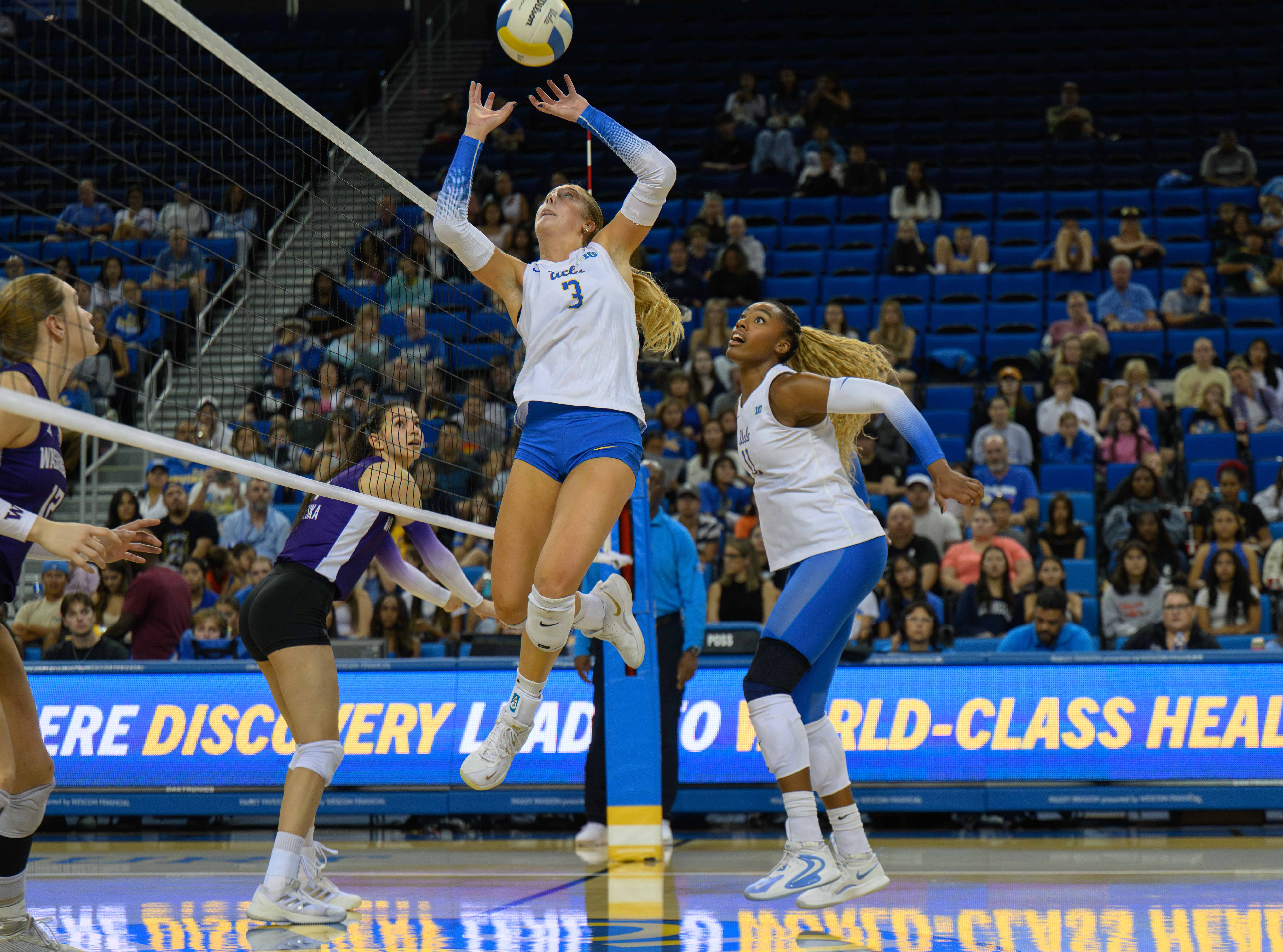 Sophomore setter Kate Duffey jump sets the ball while redshirt junior middle blocker Marianna Singletary behinds her approach behind her. (Tszshan Huang/Daily Bruin)