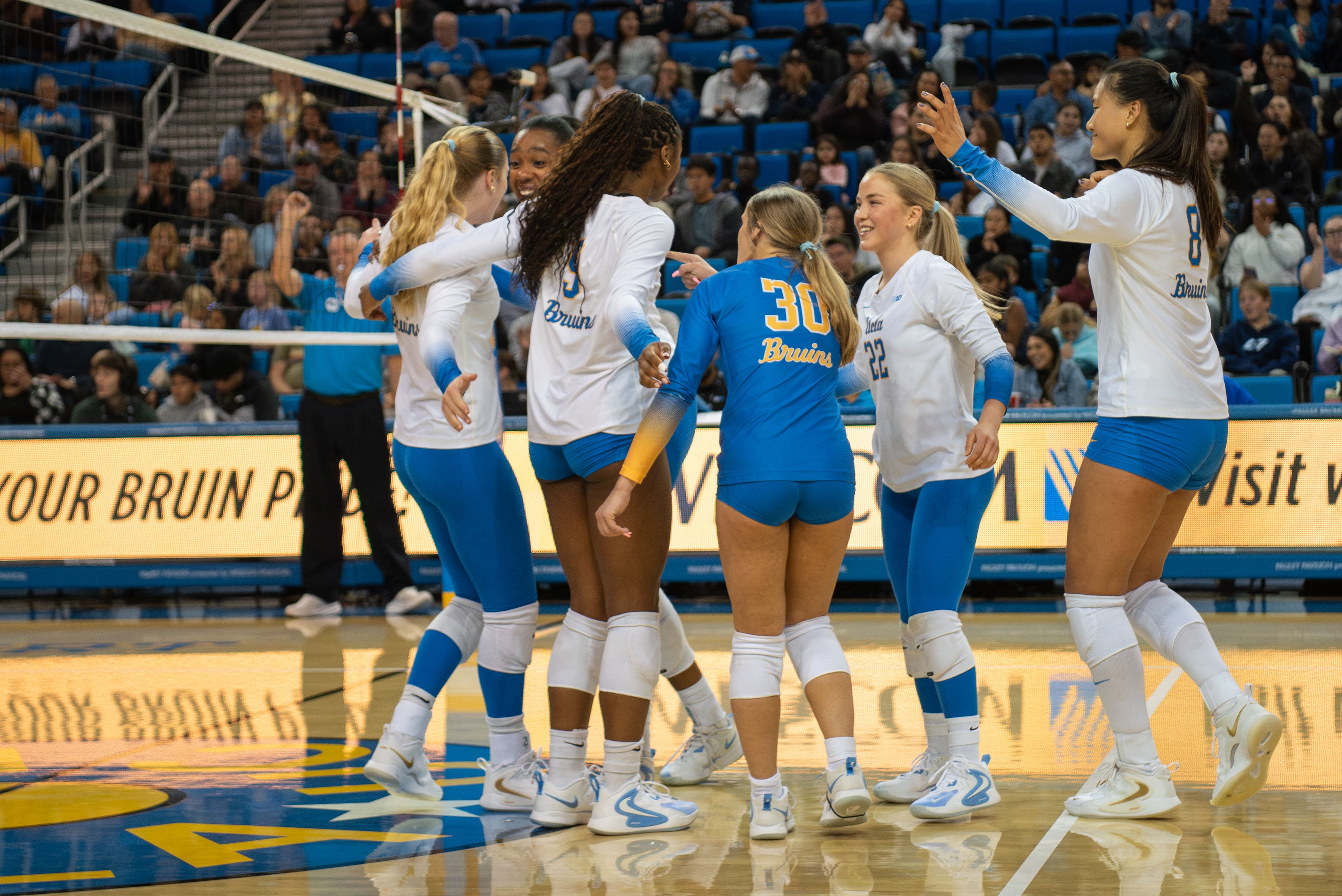 Members of UCLA women's volleyball celebrate as they walk into a huddle. (Karla Cardenas-Felipe/Daily Bruin staff)