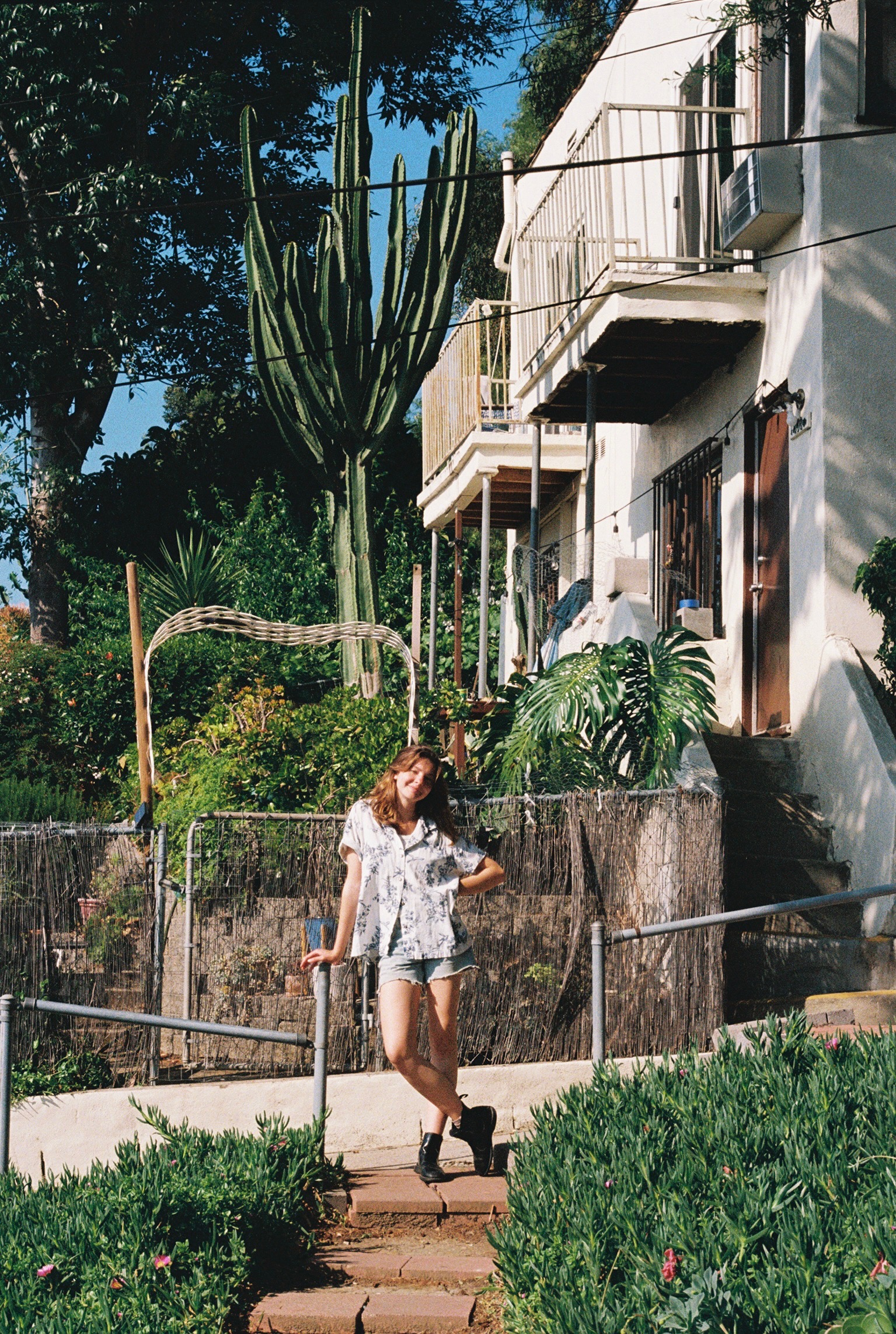 Pictured is Weissman leaning on a stair rail while wearing jean shorts and a button-up shirt. The singer-songwriter explained that, although the EP's production took longer than expected, the process allowed the band and producer to feel comfortable with each other. (Courtesy of Ava Blanchett and Katrina Weissman)