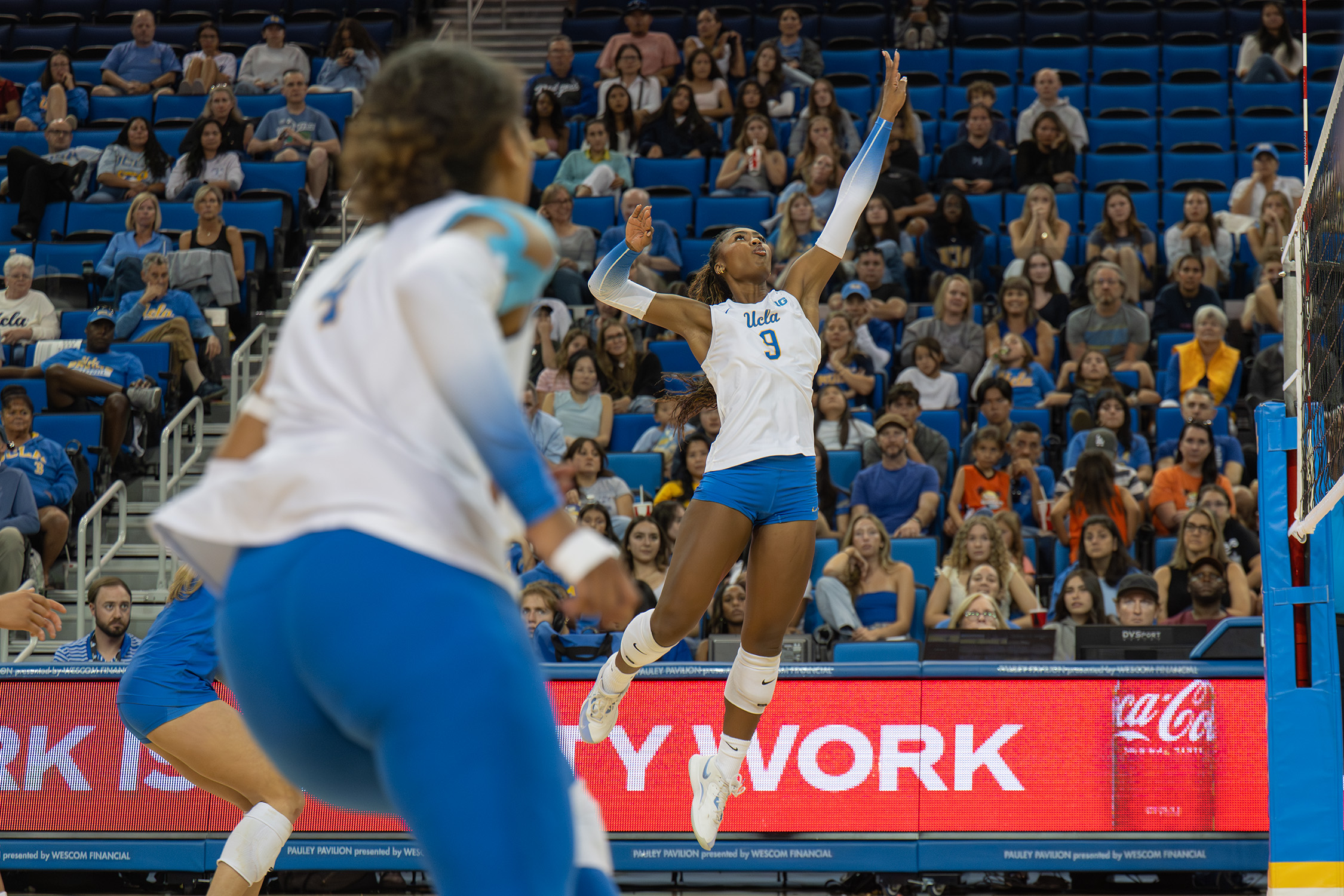 Senior outside hitter Cheridyn Leverette jumps and begins her swing to hit the ball. (Tszshan Huang/Daily Bruin)