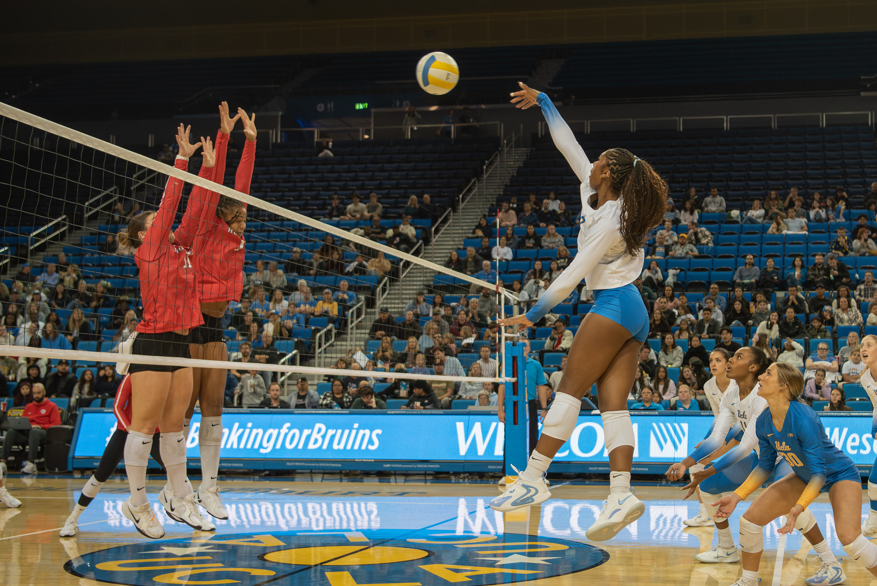 Senior outside hitter Cheridyn Leverette hits the ball as the opposing team puts up a block. (Karla Cardenas-Felipe/Daily Bruin staff)