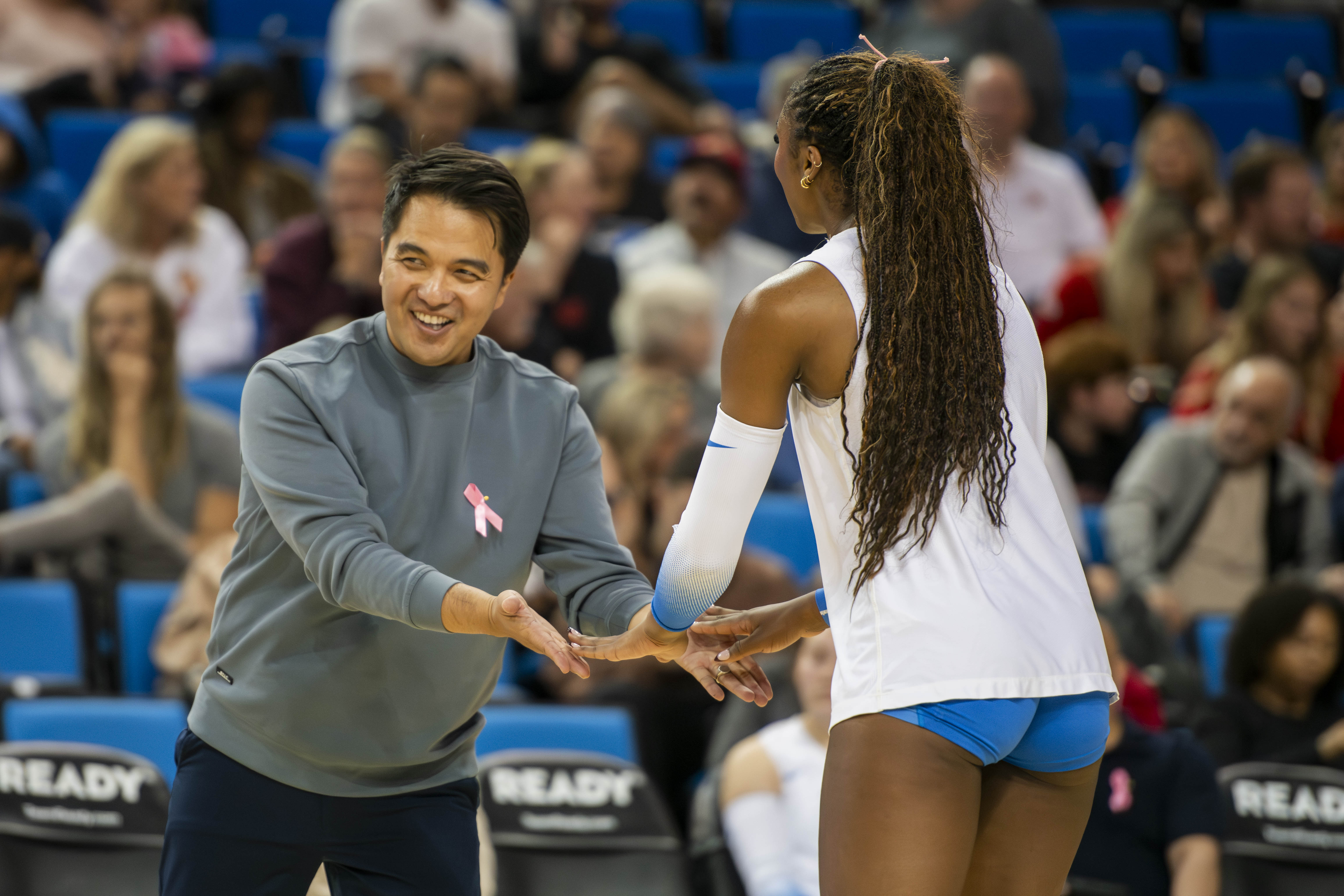 Coach Alfee Reft (left) and senior outside hitter Cheridyn Leverette (right) high fiving on the side of the court. (Edward Ho/Daily Bruin)