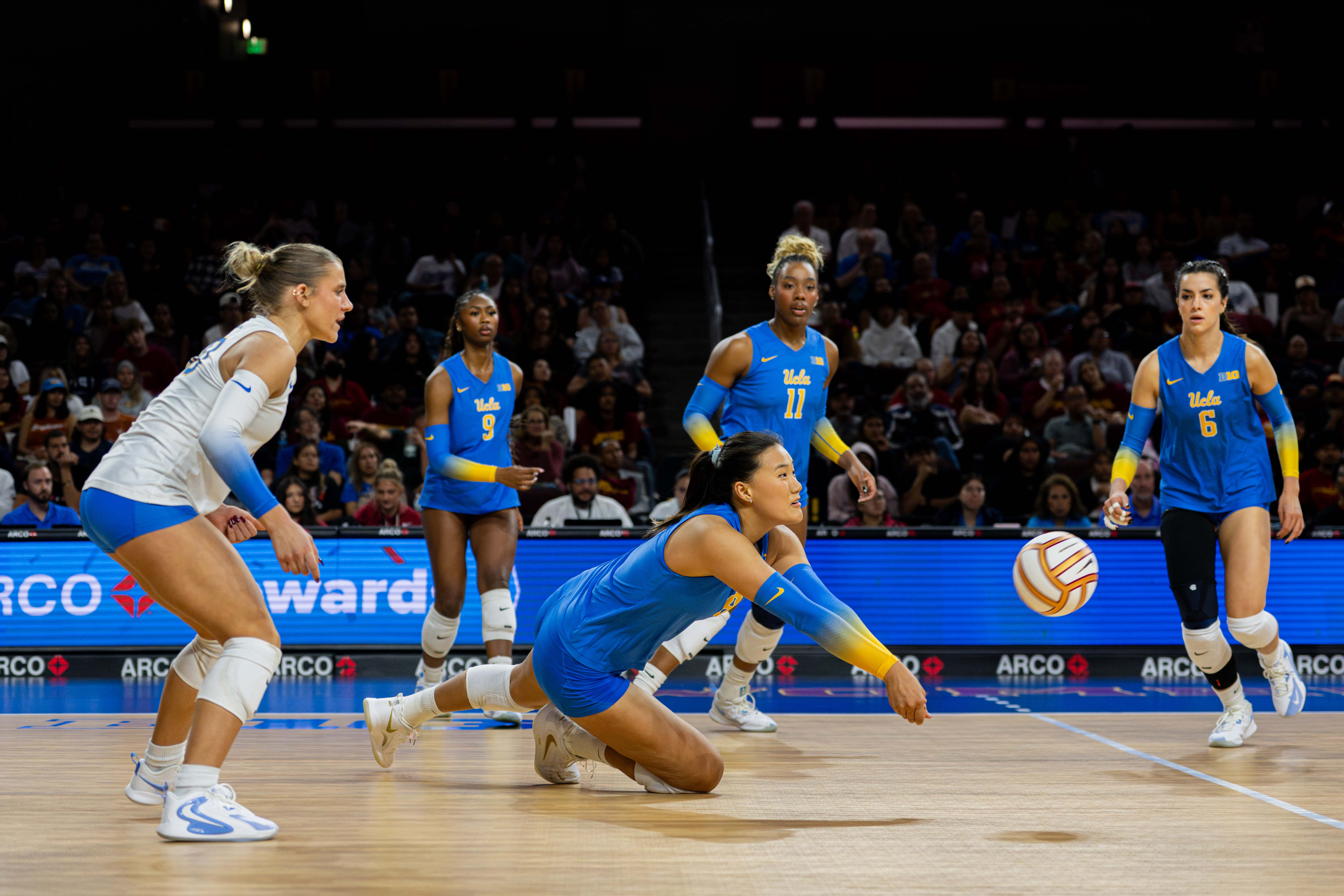 Junior outside hitter Maggie Li dives and digs a ball with her teammates around her. (Libby Li/Daily Bruin)