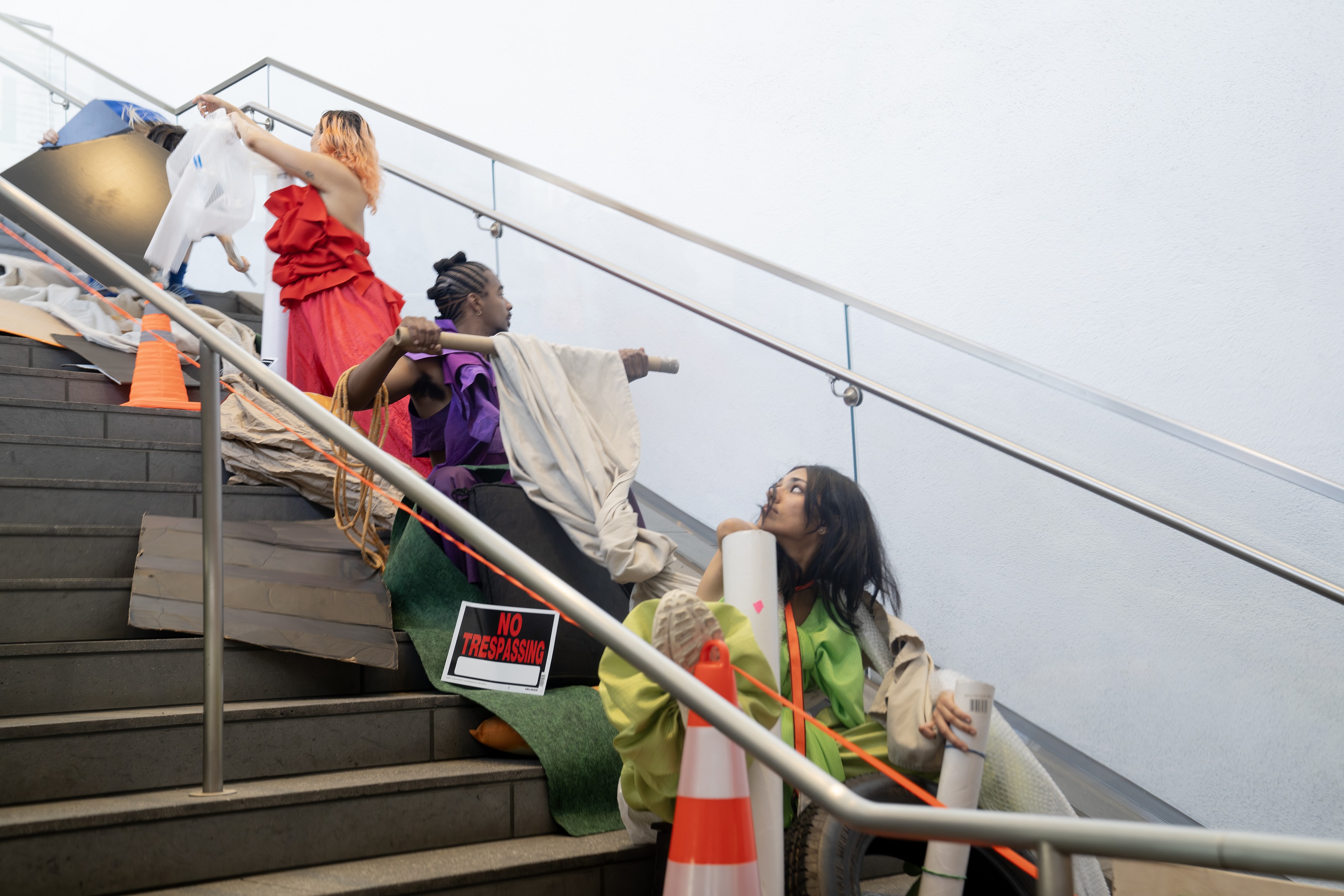 Pictured are three “Unmade” performers at the Hammer’s staircase, surrounded by multiple of the show’s props, including a sign that reads “NO TRESPASSING.” The “Made in L.A.” co-curator, Essence Harden, said Rawls’s show embodies the qualities of LA’s art ecosystem, its creativity and chaos. (Courtesy of Amina Cruz)