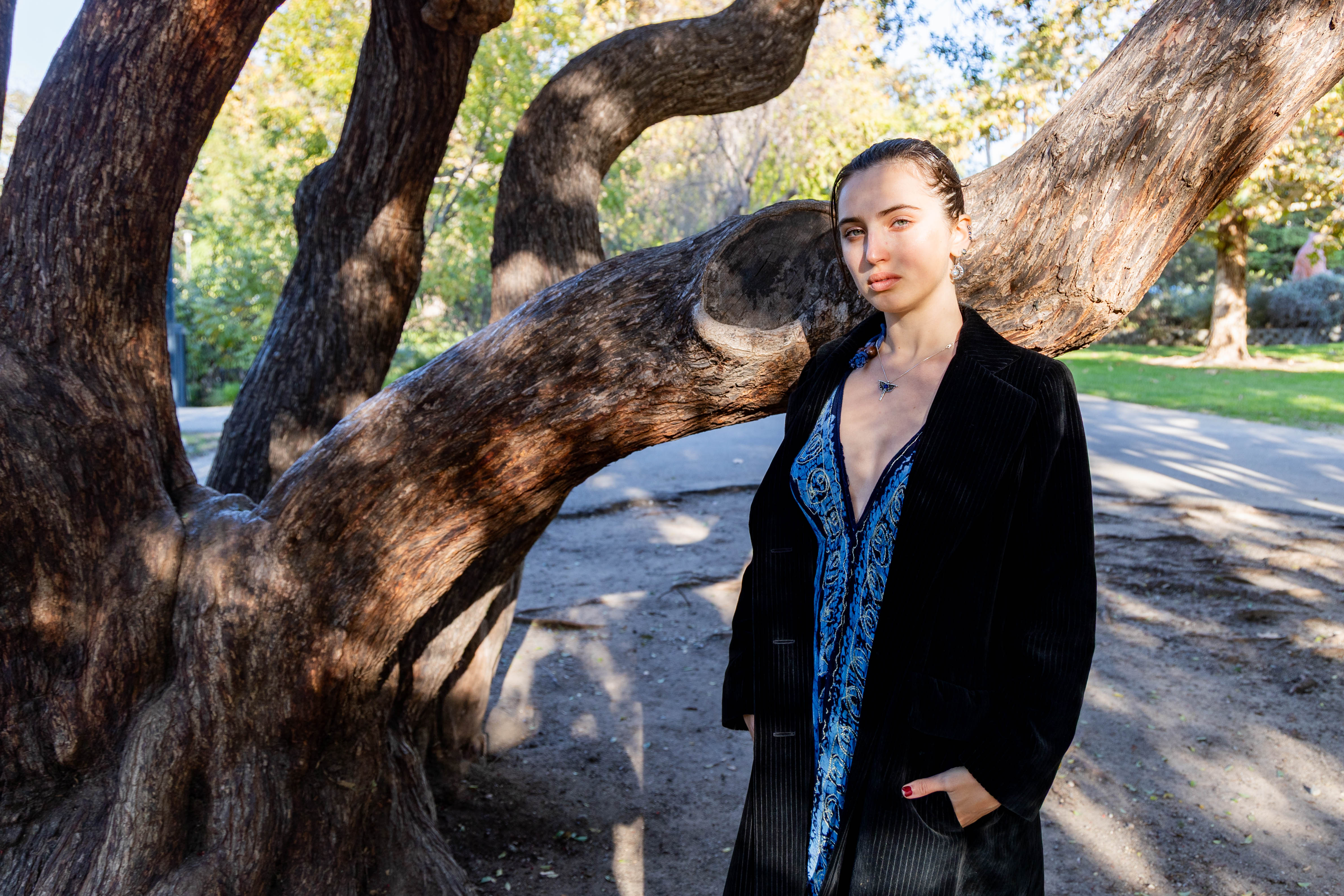 Posing in front of a tree with a black coat is the ethnomusicology graduate. Regarding the title of her LP, Dry said she based her decision on the track that felt like a representation of her, and that allowed all songs to become part of a single universe. (Chenrui Zhang/Daily Bruin)