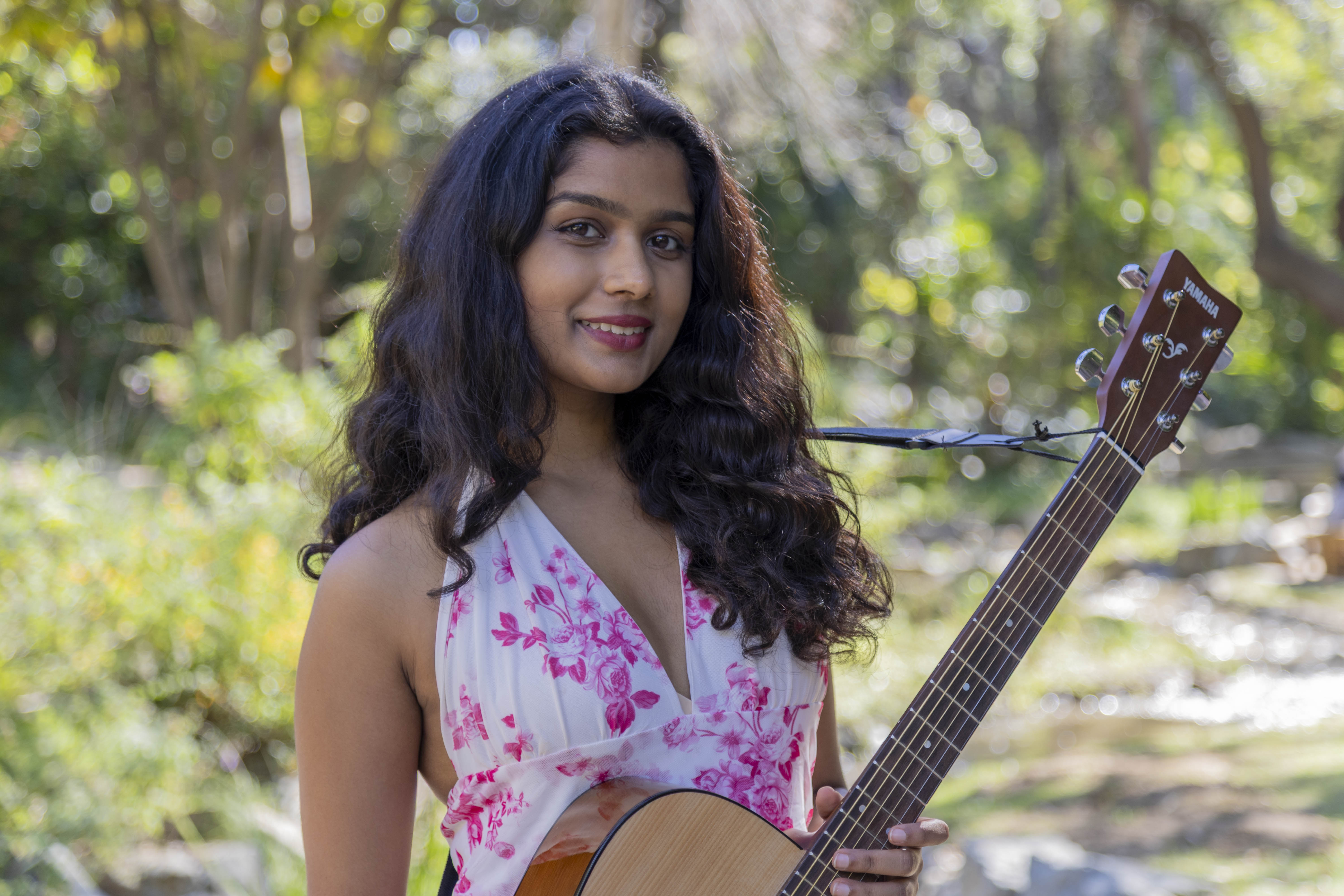 Pathak poses for a picture outdoors while wearing a white dress with a pink, flowery pattern. The public health student said before releasing her original work, she had some experience in the music world, from winning songwriting events to forming a band, performing in senior homes, and schools. (Jiah Jung/Daily Bruin)