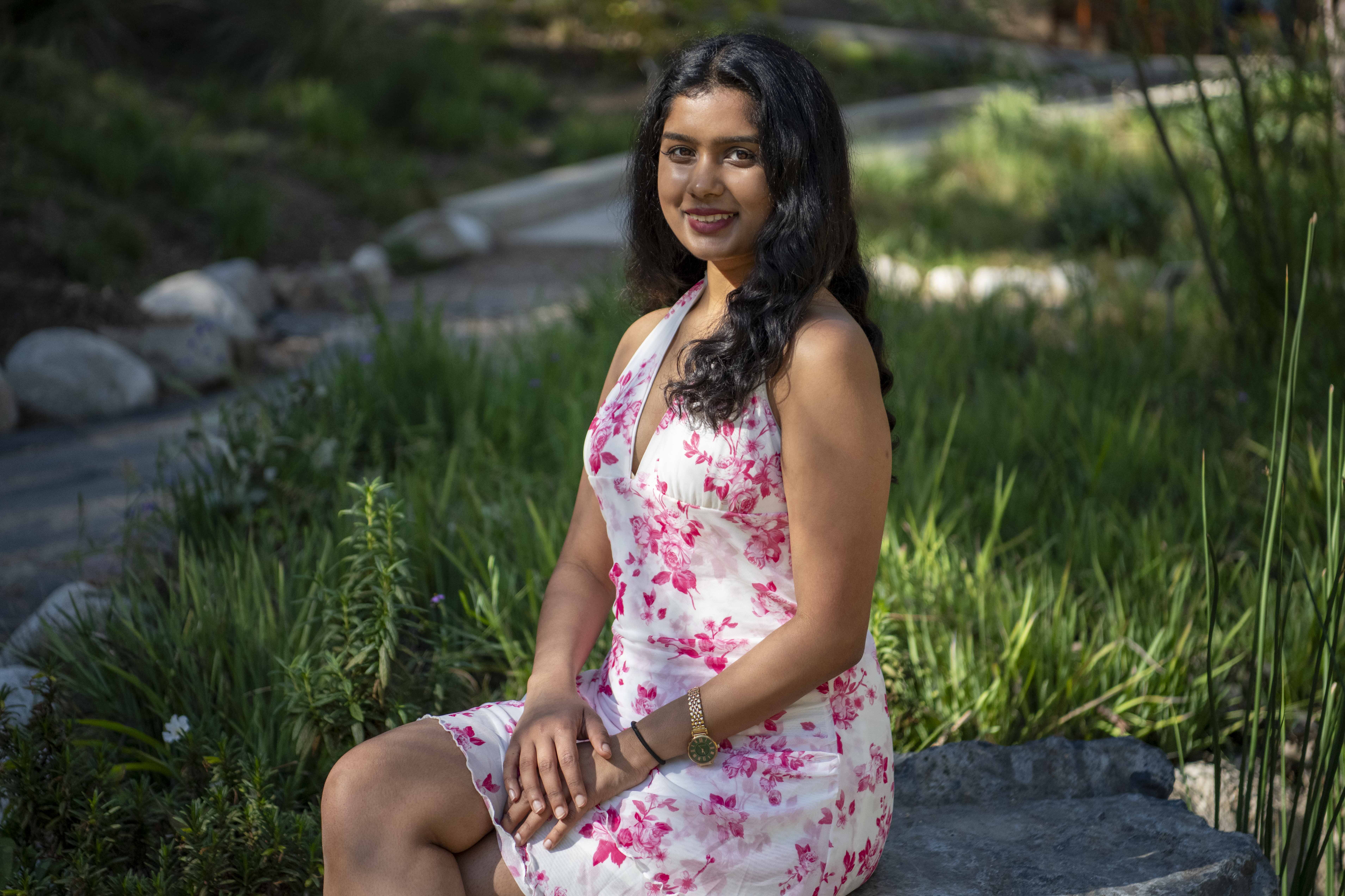 Pathak is sitting on top of a stone surrounded by greenery. The student musician said her musical inspiration includes pop icons such as beabadoobee, jazz-leaning acts like Norah Jones and soulful pop artists like Arijit Singh. (Karla Cardenas-Felipe/Daily Bruin staff)