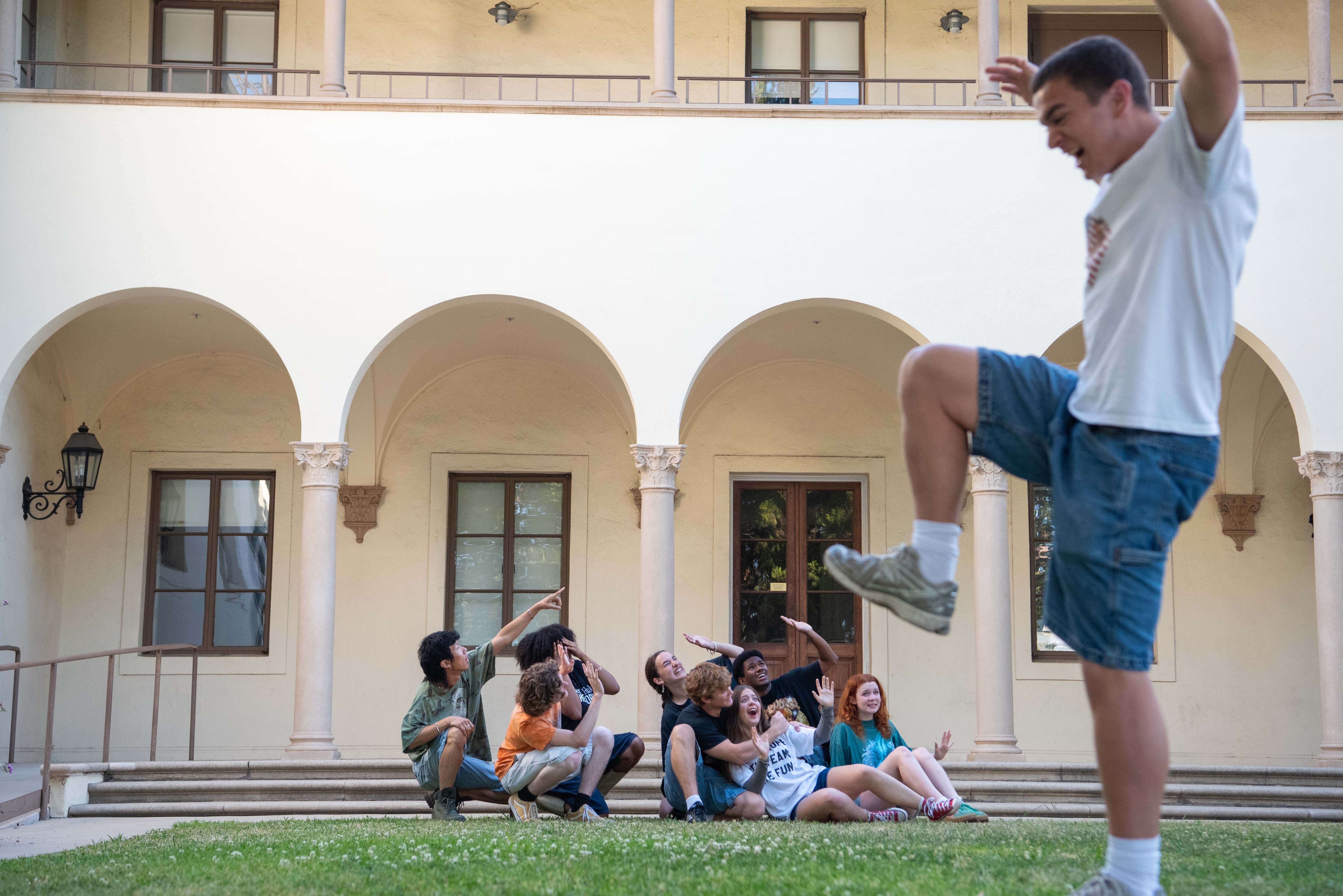 Pictured is an optical illusion with eight Company members sitting at a set of steps while acting frightened as one member, closer to the camera, pretends to step into them. Since all previous members of the group graduated, Company co-director Sean Anderson said the group has been able to be more experimental with their new work. (Izzy Greig/Daily Bruin)