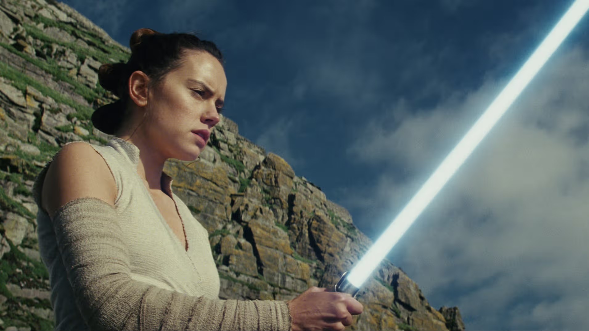 Daisy Ridley, who plays Rey in “Star Wars: Episode VIII - The Last Jedi,” looks at a blue lightsaber. “The Last Jedi” premiered in 2017. (Courtesy of Academy Museum of Motion Pictures)