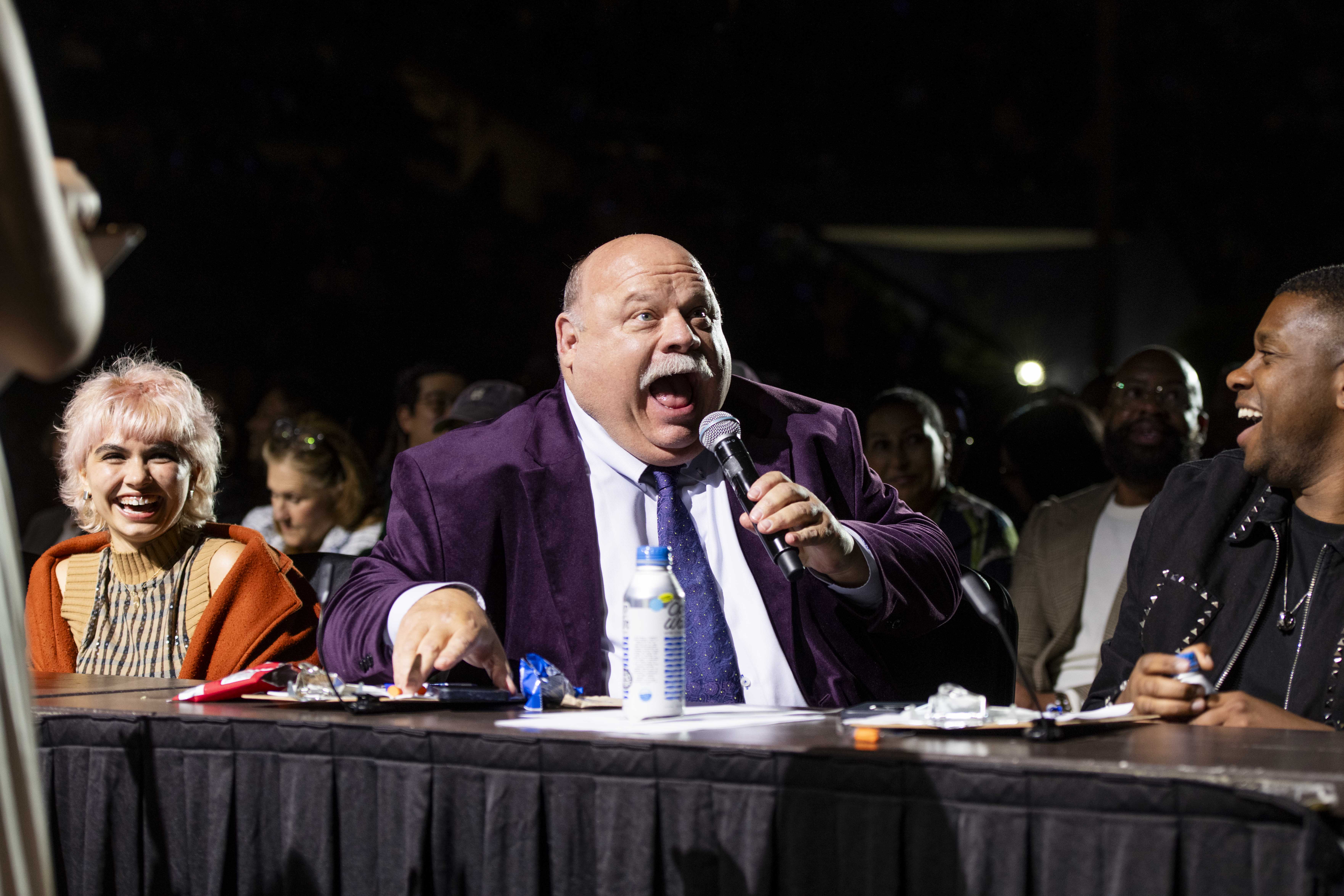 Line of celebrity judges sitting at a pannel where Kevin Chamberlin is seated in the middle, talking into the microphone. Spring Sing is here again, and the performers are readying themselves for the stage with the kind of dedication that deserves a packed house (Leydi Cris Cobo Cordon/Daily Bruin senior staff)