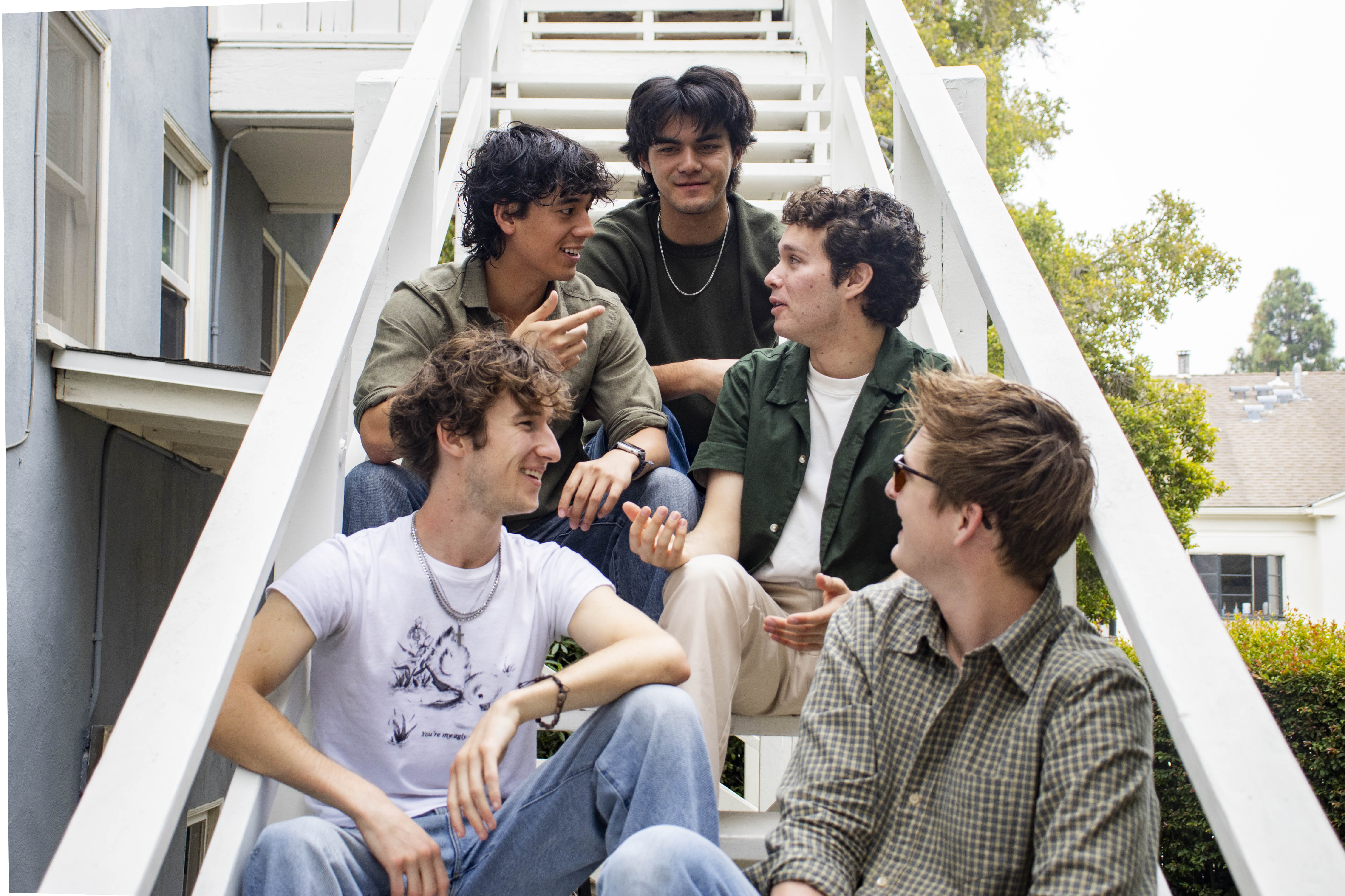 The five members of The Situations are shown sitting on a white flight of stairs. All members have overlapped in different bands throughout the years, but first met at SLAM! UCLA, Breister said. (Ruby Galbraith/Daily Bruin staff)