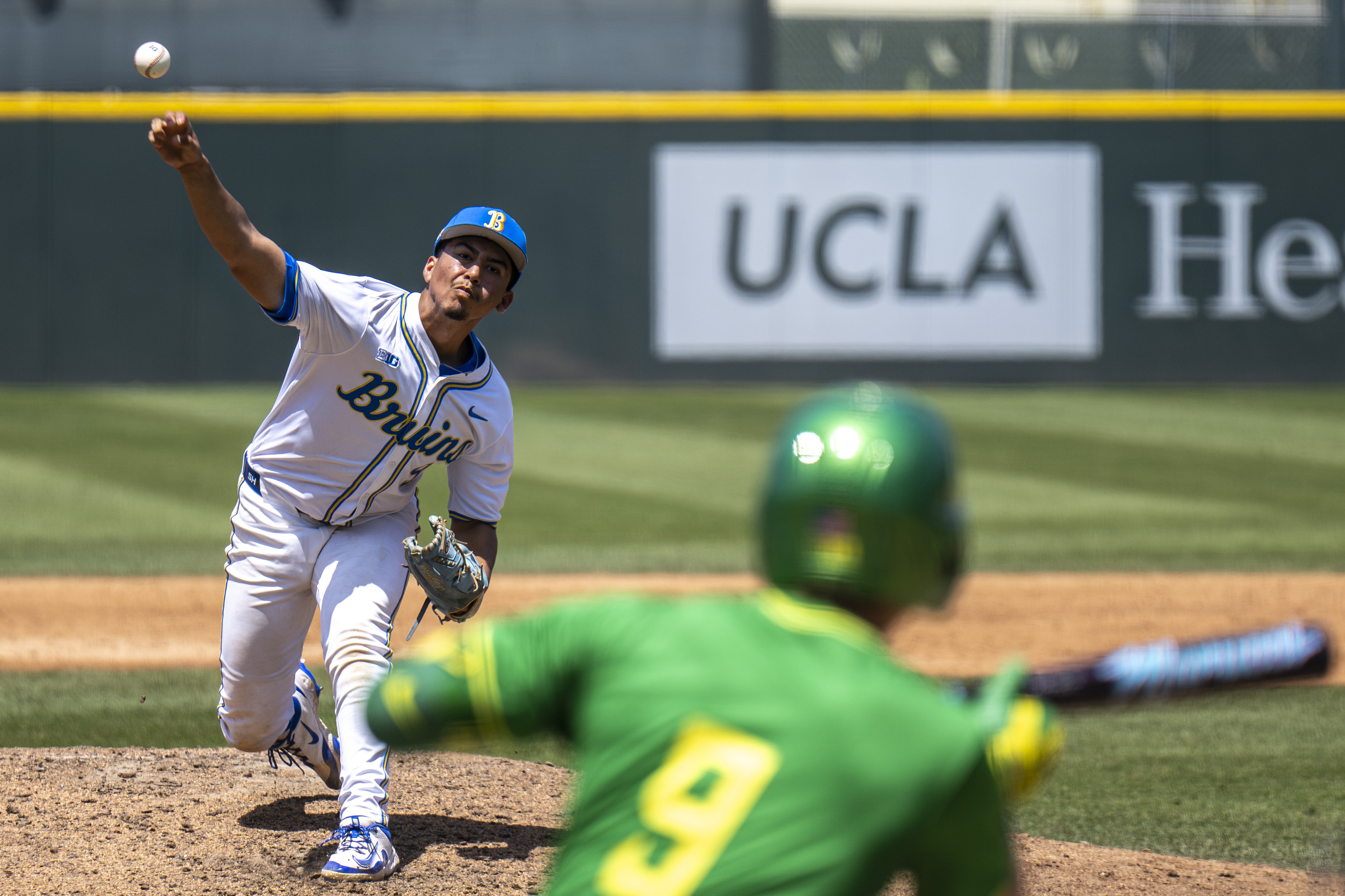 Freshman right-hander Angel Cervantes delivers home as Oregon shortstop Maddox Molony shows bunt. (Kai Dizon/Daily Bruin senior staff)