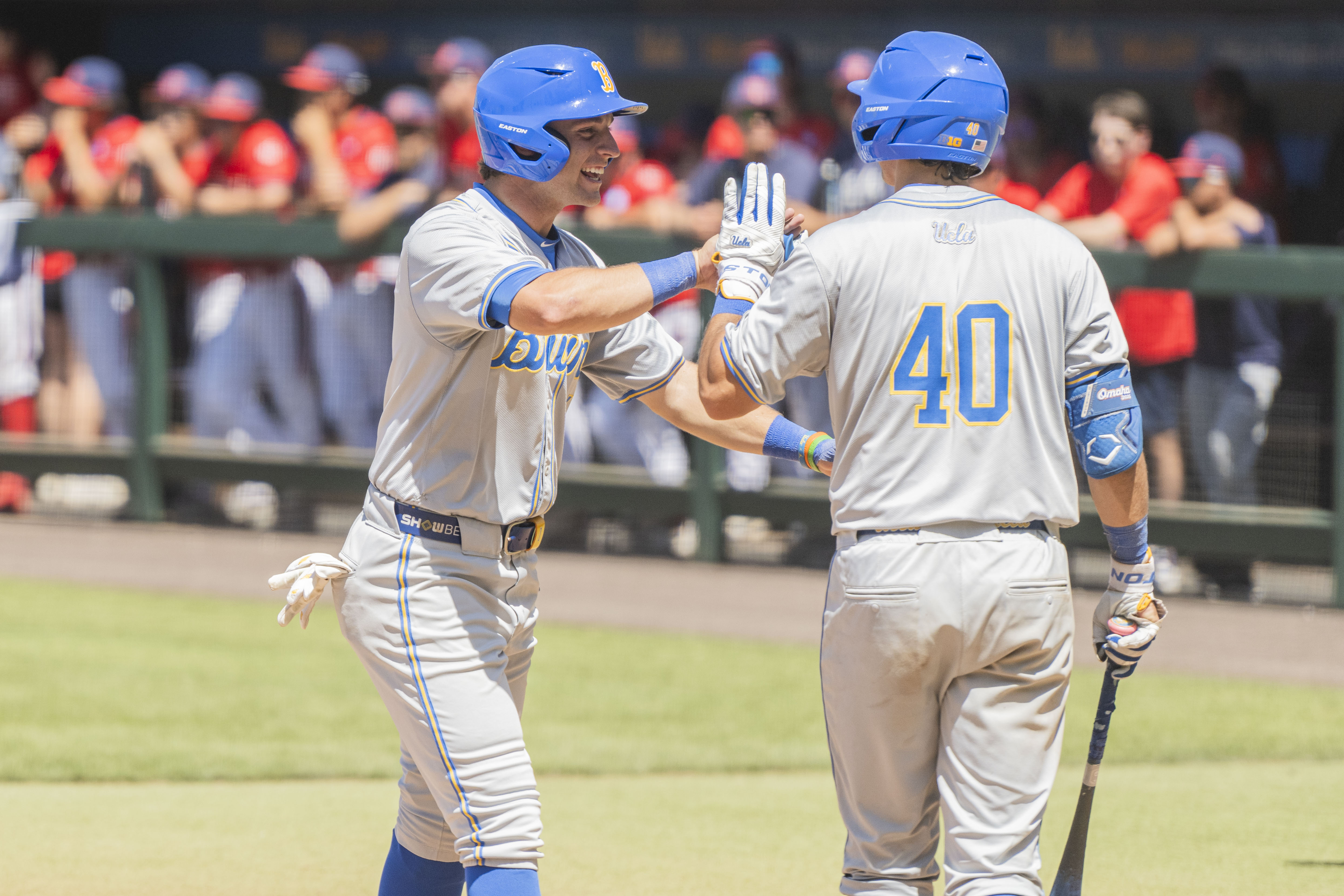 Cholowsky high fives junior catcher Cashel Dugger after reaching scoring. (Kai Dizon/Daily Bruin senior staff)