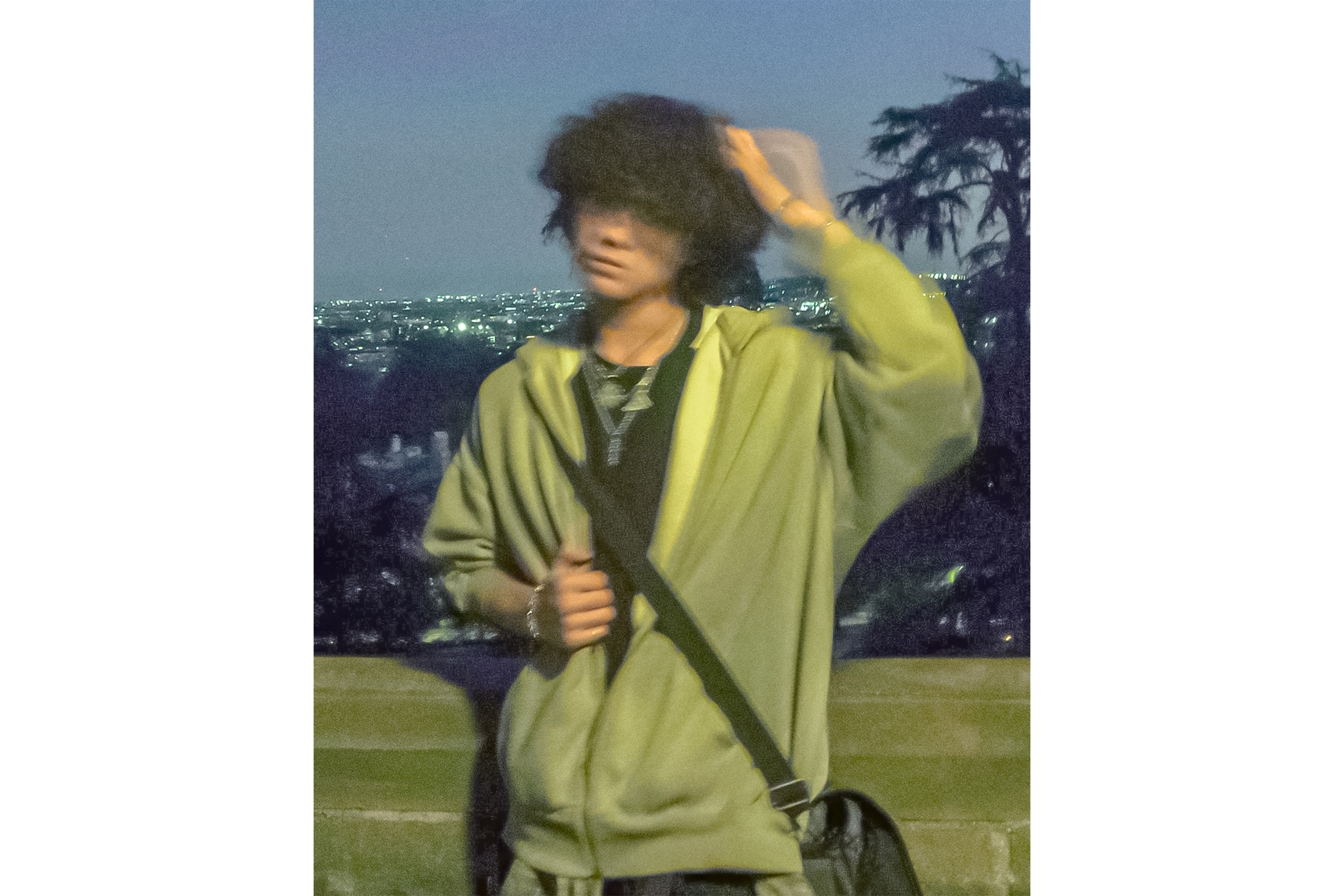Dea stands in front of the camera at dusk with the skyline of the city behind him, wearing a gray hoodie. The artist said his six-track EP creates a cohesive storyline that ties each song together. (Courtesy of Dea/Altered from original)
