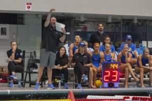 Former UCLA women’s water polo coach Adam Wright stands by the pool deck and points while holding a sheet to his mouth. Wright led the program to its first national championship since 2009 in 2024. (Daily Bruin file photo)
