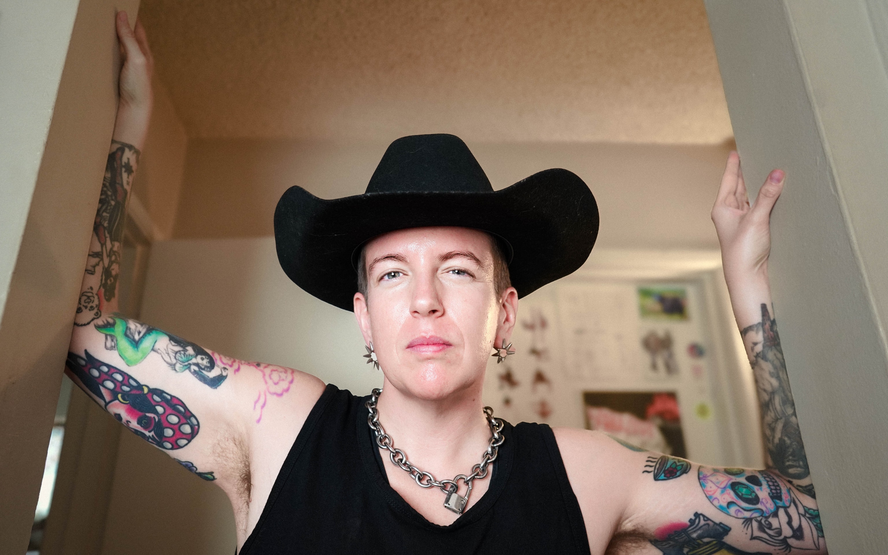 The drummer poses between a doorframe and a wall, wearing a black hat. They earned a doctorate in musicology this year after completing an undergraduate and master's degree at the university. (Courtesy of Esther Godoy)