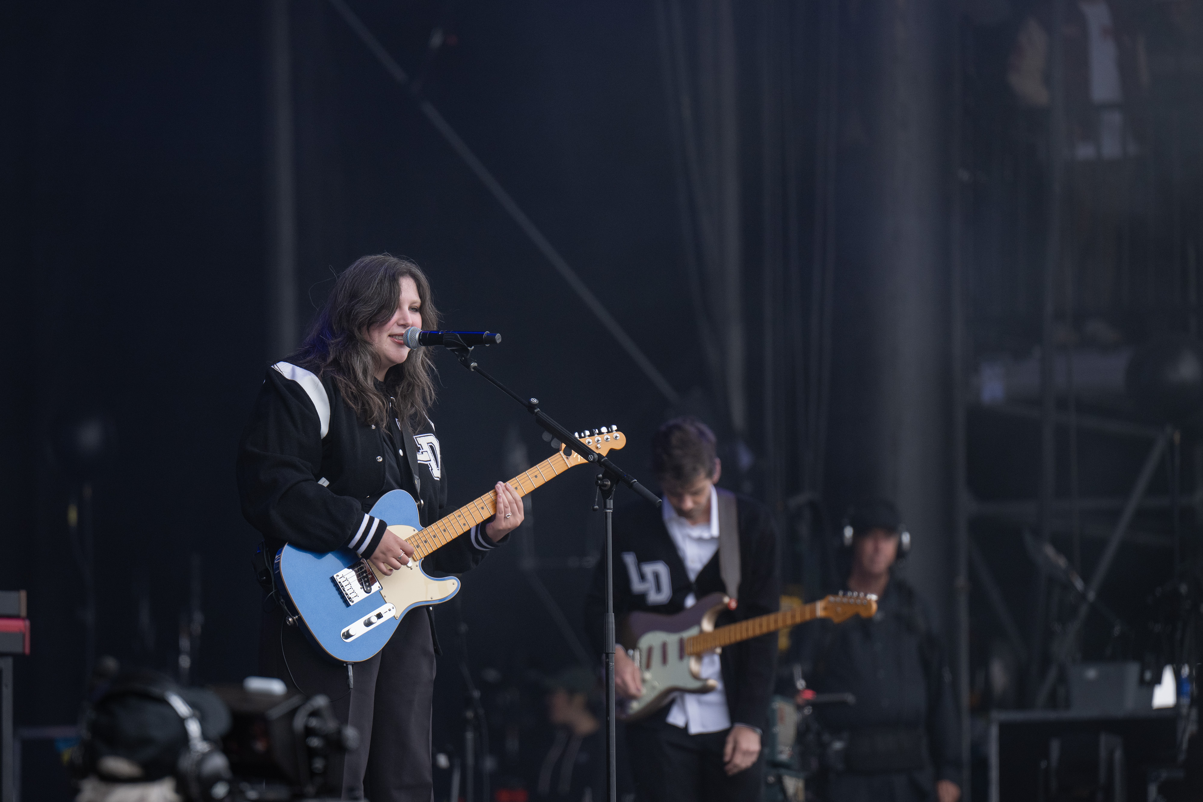 Lucy Dacus sings into a microphone while playing a blue electric guitar. The Grammy Award-winning artist played songs such as “Night Shift" in her 11-song set. (Leydi Cris Cobo Cordon/Daily Bruin senior staff)