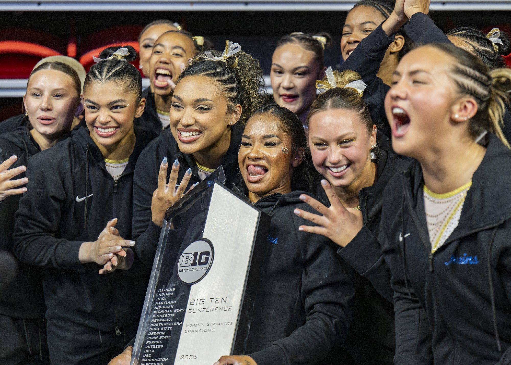 The UCLA gymnastics team holds the Big Ten trophy. The Bruins went back-to-back, winning the conference tournament in 2025 and 2026. (Zimo Li/Daily Bruin senior staff)