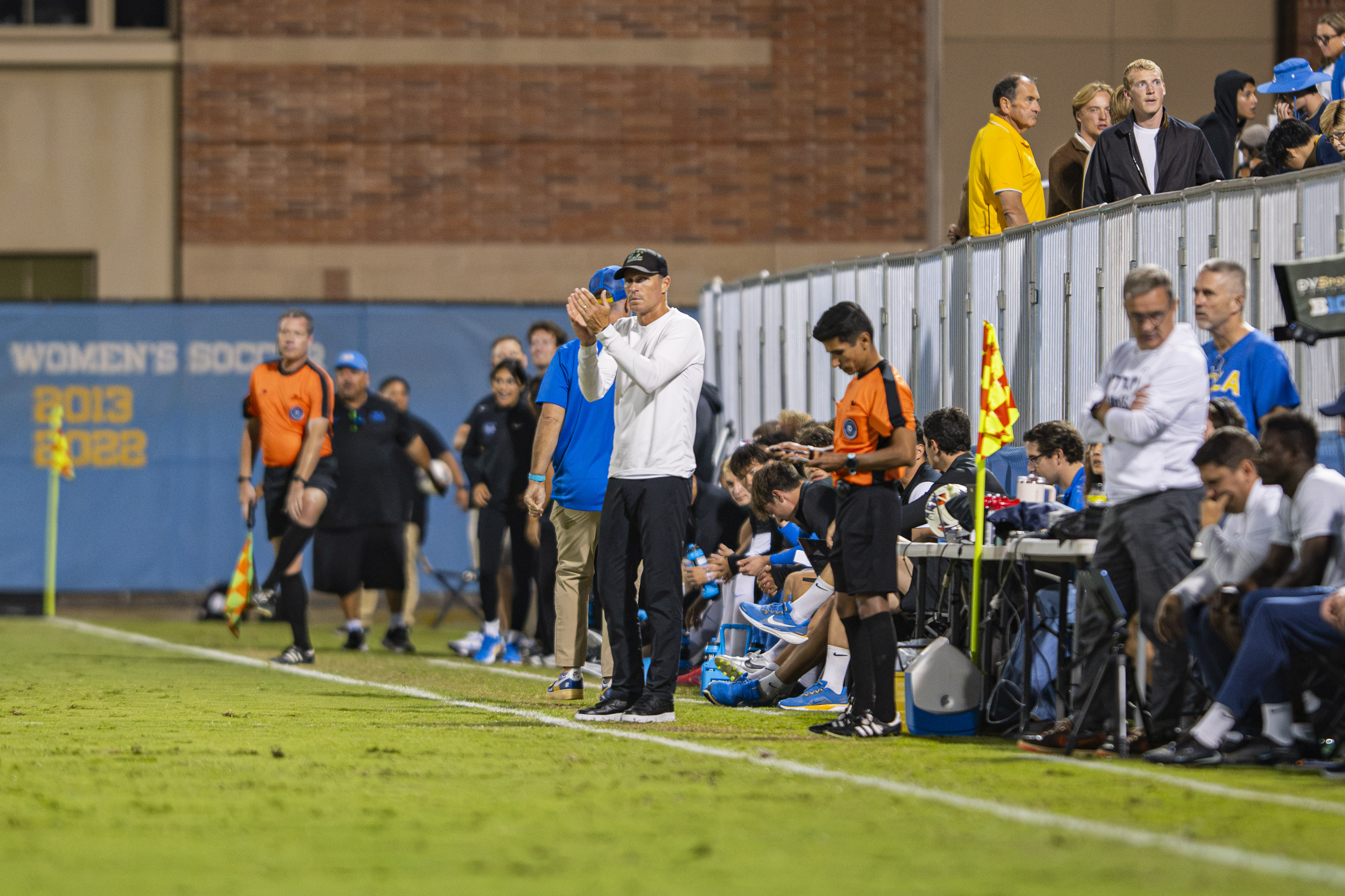 Coach Ryan Jorden stands on the sideline and claps his hands. Jorden enters his eighth season with the Bruins. (Libby Li/Daily Bruin)