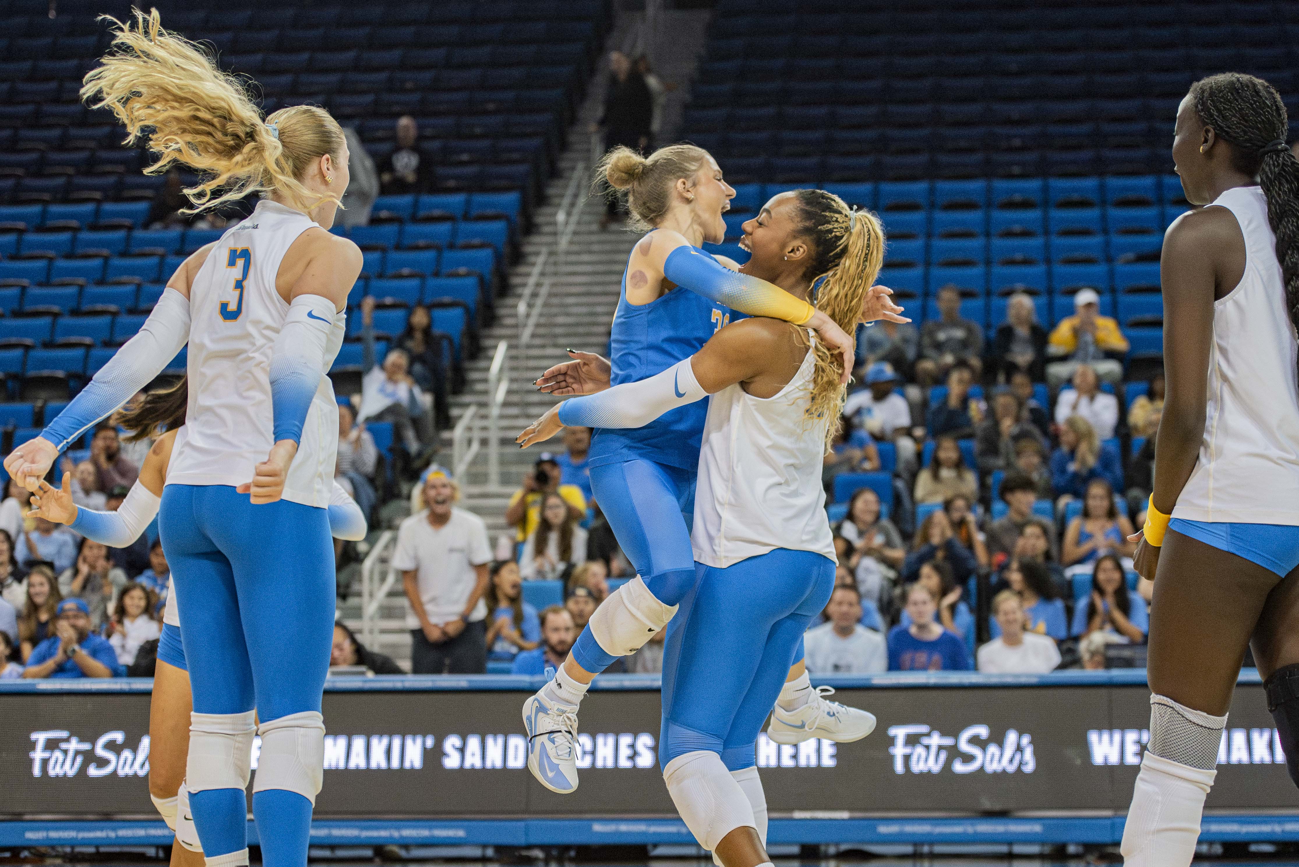 Junior libero Lola Schumacher (left) jumps into fifth-year middle blocker Marianna Singletary's arms at Pauley Pavilion. (Brianna Carlson/Daily Bruin staff)