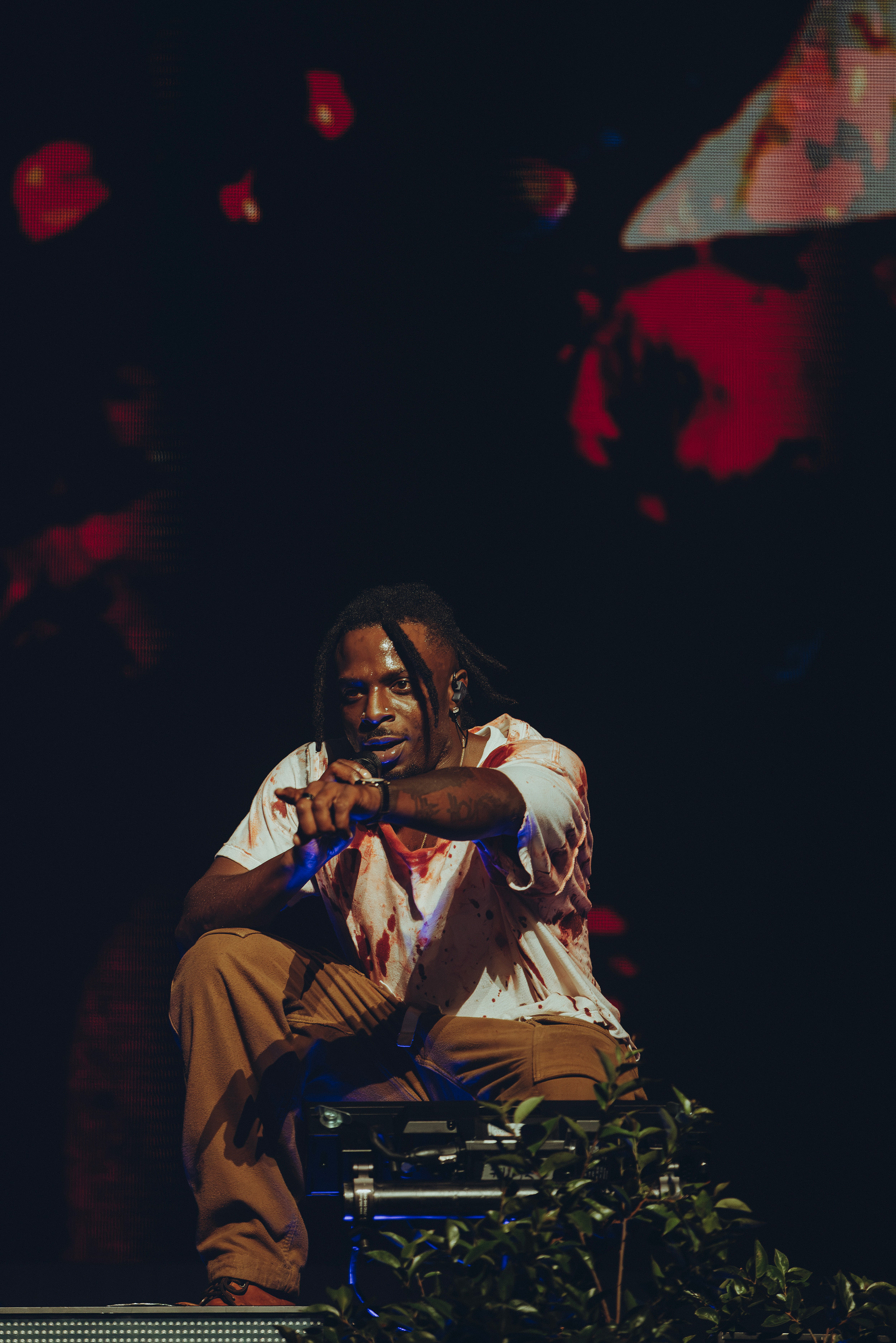 Rashad sits on stage and points to the crowd. The “RIP Young” rapper opened his set with “THE NEW SUBLIME,” the intro track to his most recent album “IT’S BEEN AWFUL." (Courtesy of Wes & Alex Photography)