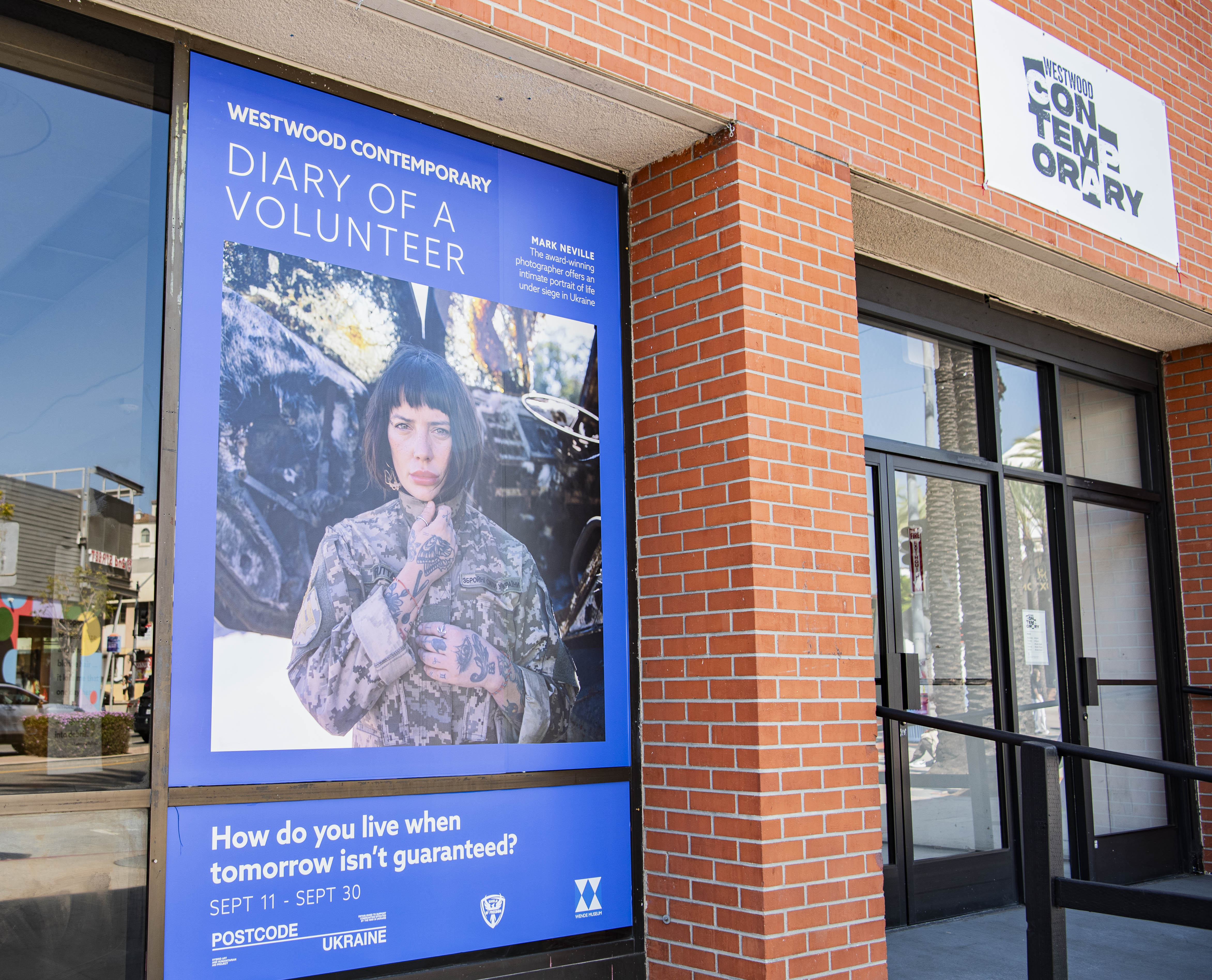 The exhibition's central image, a color portrait of a woman in a military jacket, is printed on vinyl outside the Westwood Contemporary gallery entrance. Neville said the subject is Sasha, a stylist turned soldier. (Crystal Tompkins/Daily Bruin senior staff)