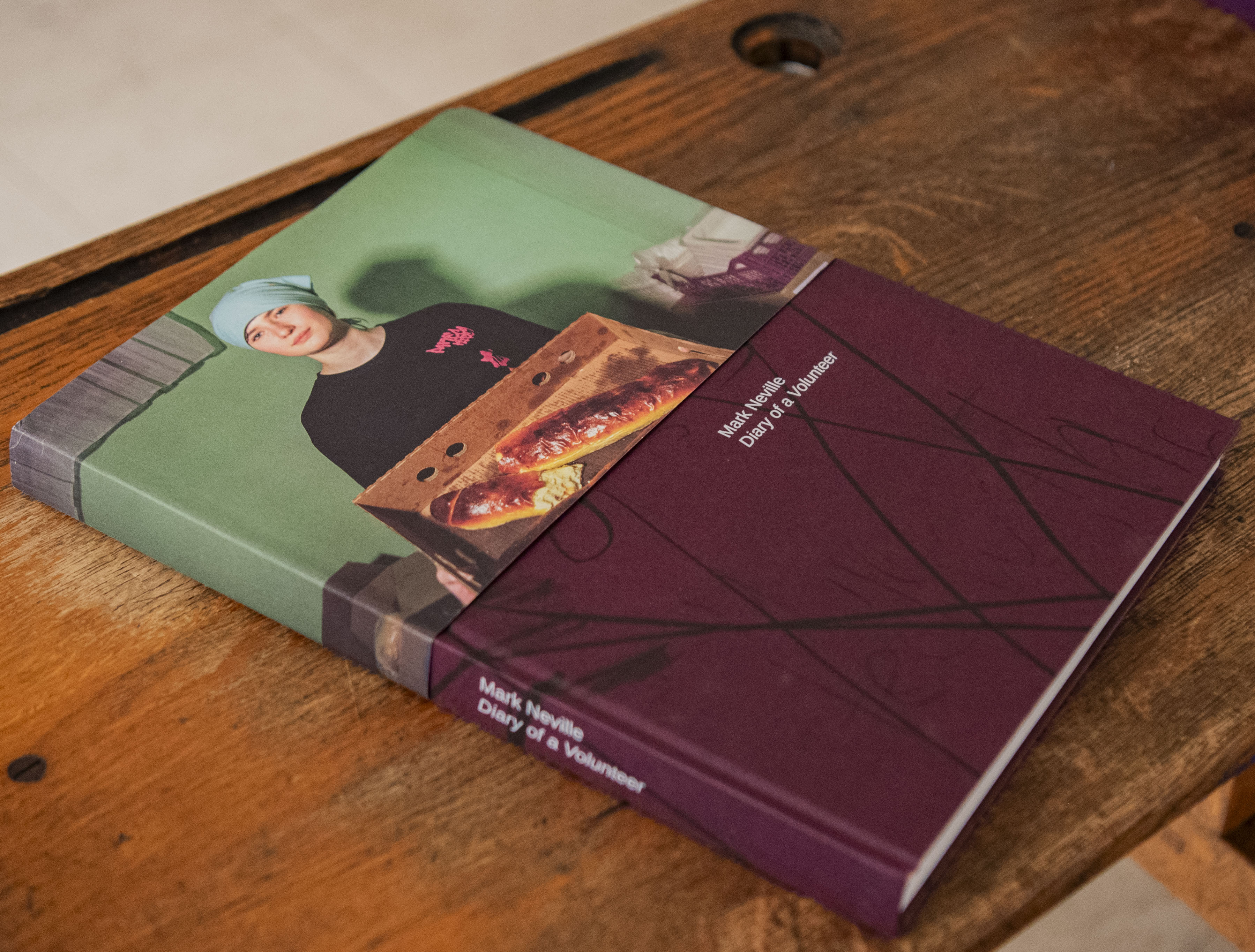 Mark Neville's book is displayed on a wooden table. “Postcode Ukraine: Diary of a Volunteer” is based on Neville's book, which offers his personal record of the front lines through more than 100 photographs. (Crystal Tompkins/Daily Bruin senior staff)