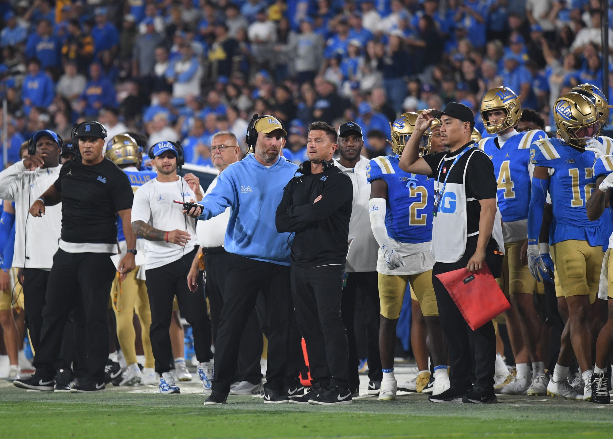 Defensive coordinator Colin Hitschler (left) talks to Chesney, who has his arms crossed, on the sideline. (Kai Dizon/Assistant Photo editor)