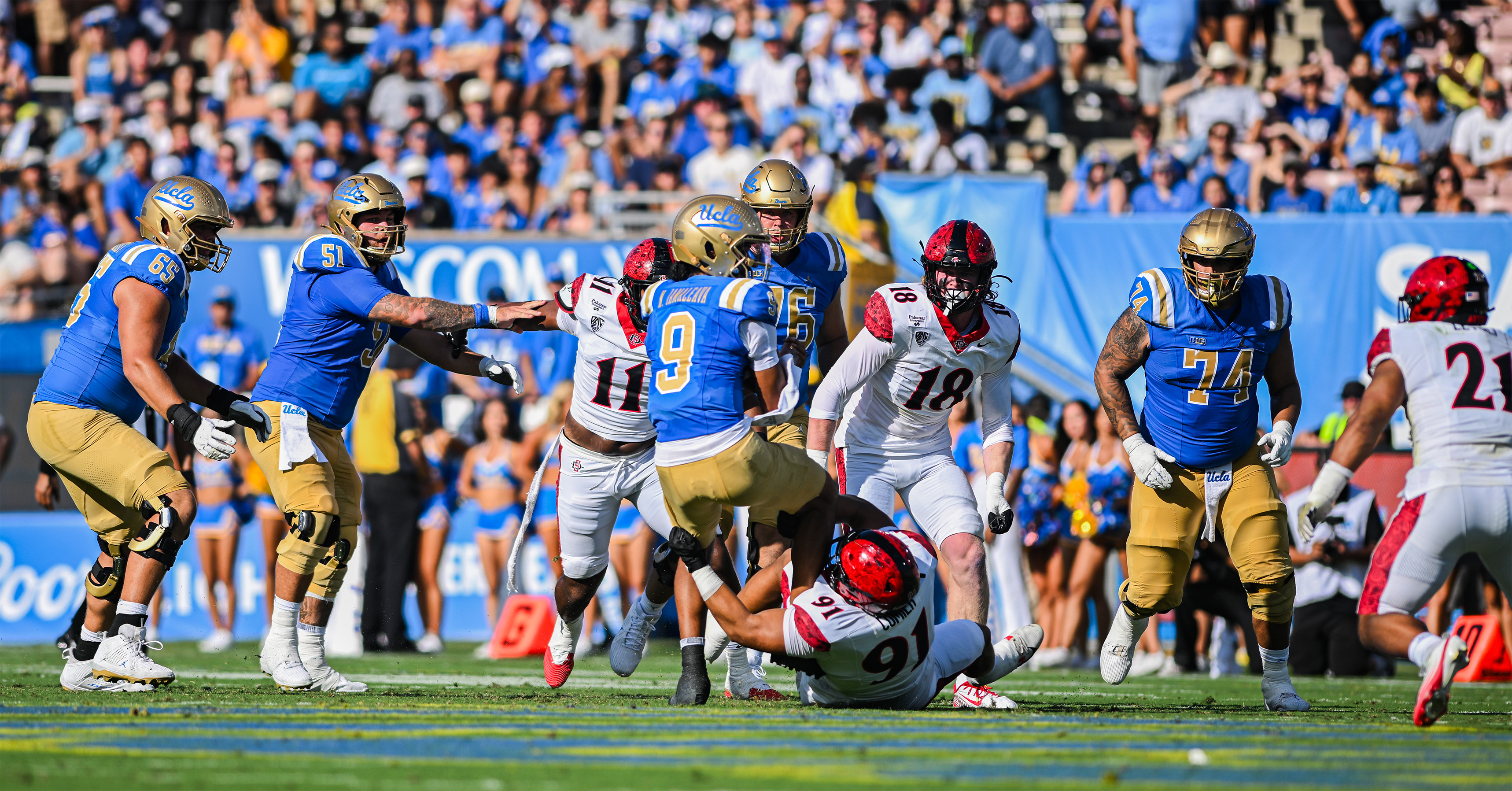 An Aztec defender wraps his arms around senior quarterback Nico Iamaleava's legs in an attempt to bring him down. (Presley Liu/Daily Bruin senior staff)