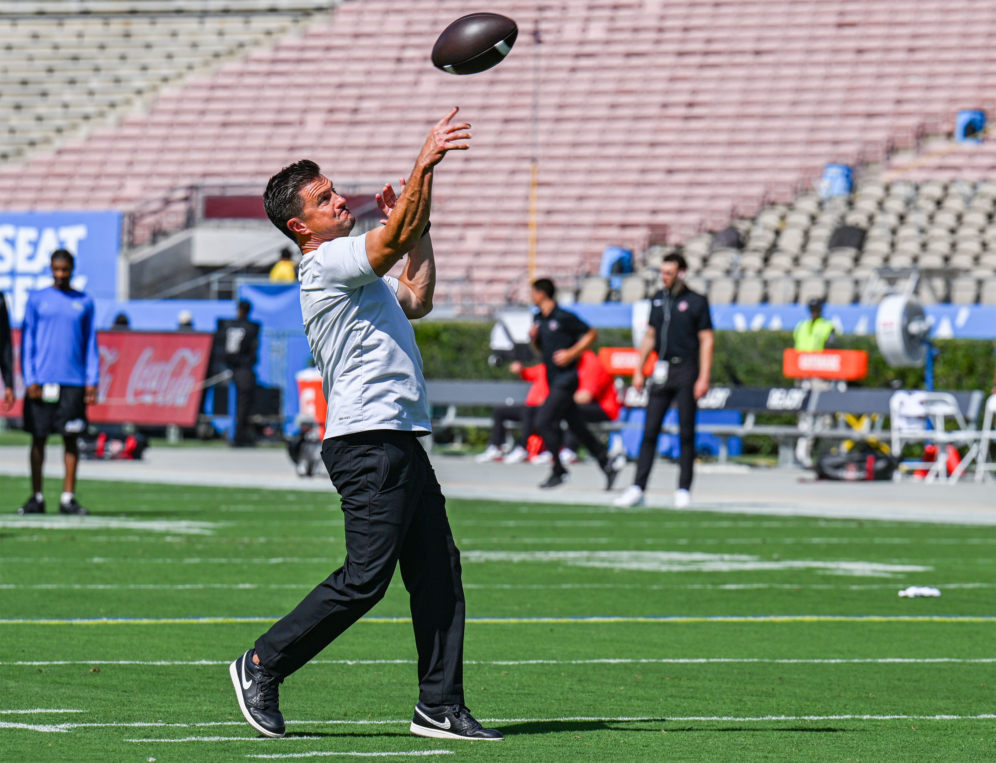 UCLA football coach Bob Chesney hurls a football into the air ahead of his team’s game against California on Saturday. (Presley Liu/Daily Bruin senior staff)