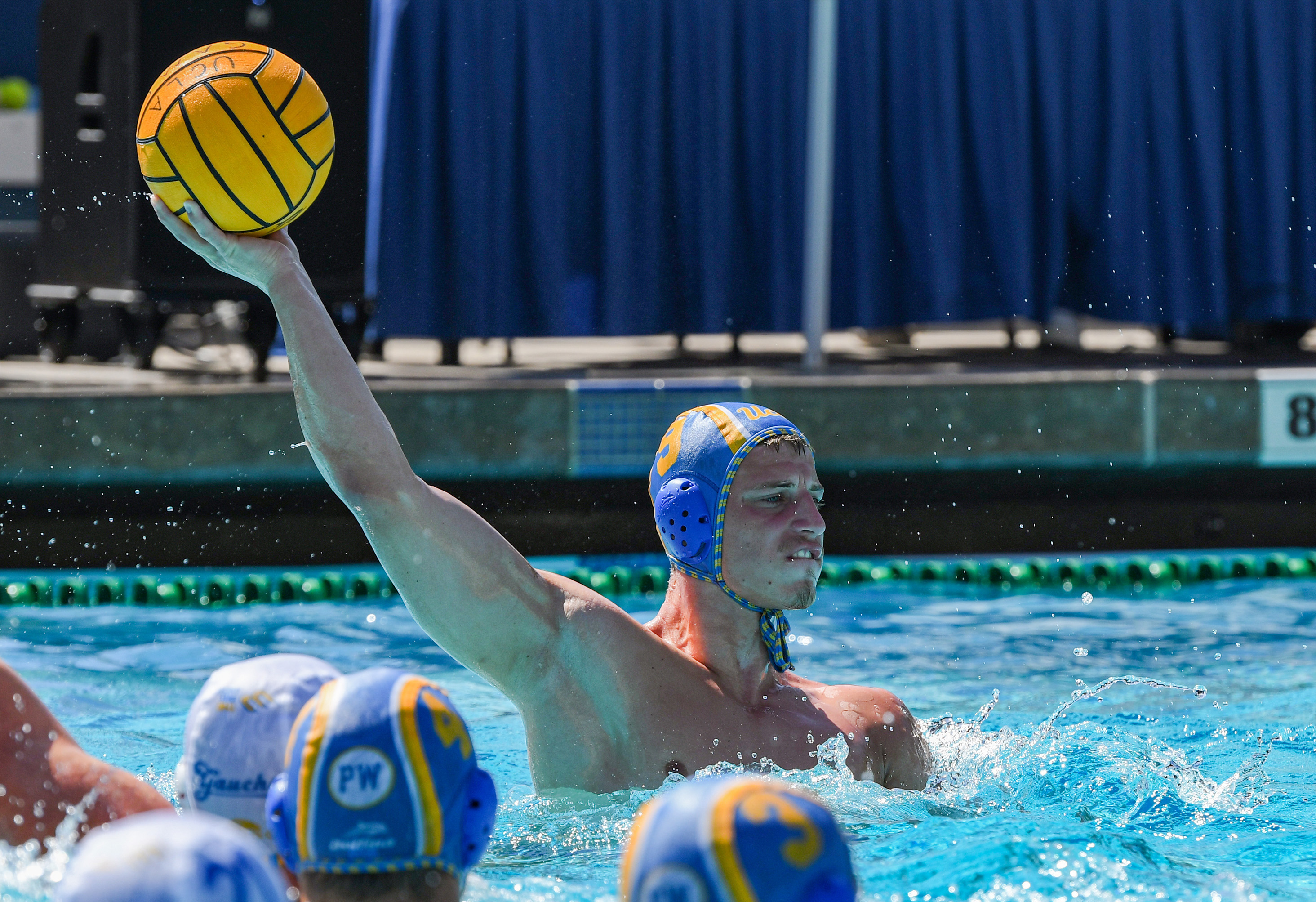 Gladović holds the ball high above the water in his right arm. (Elle Smith/Daily Bruin staff)