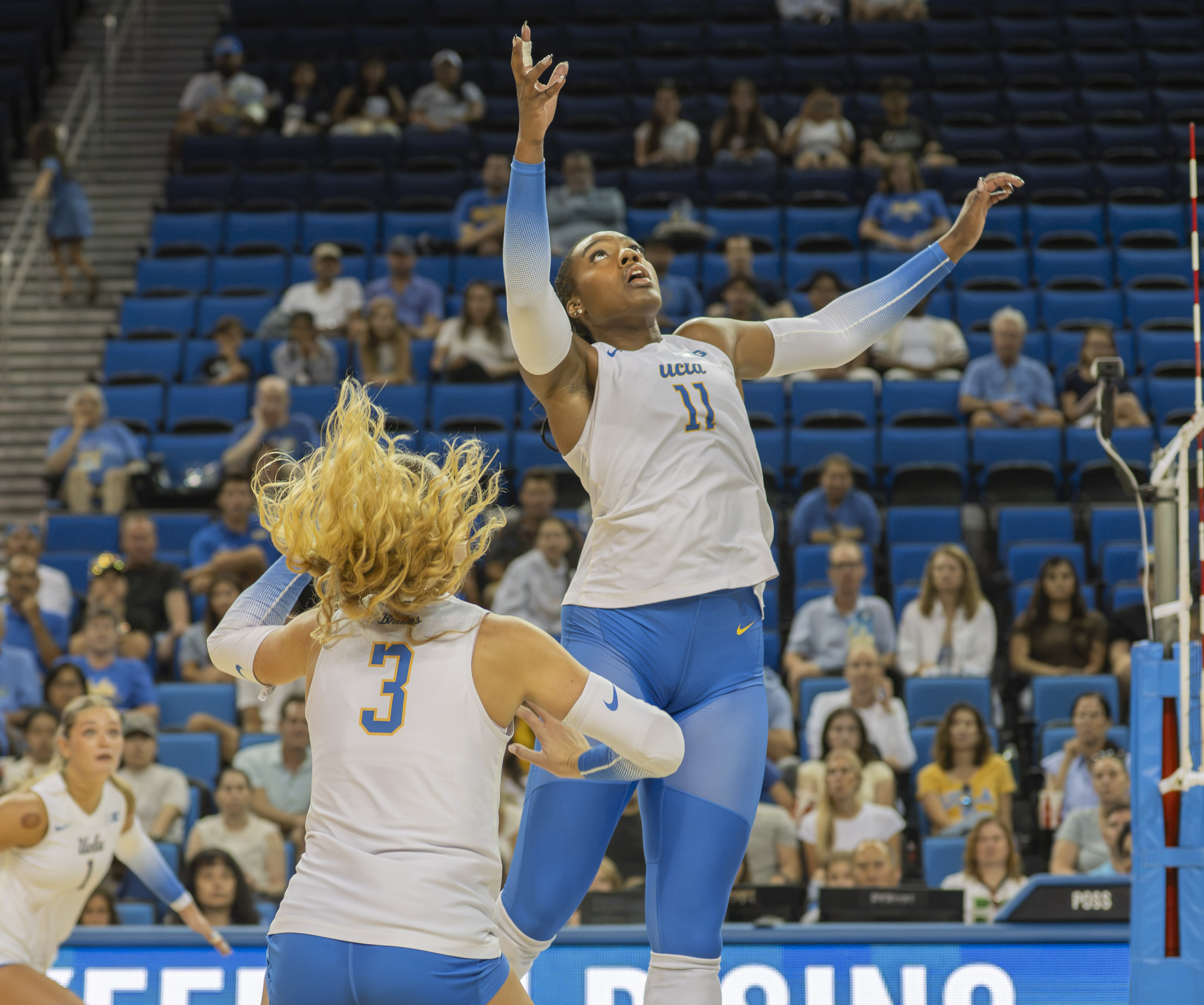 Fifth-year middle blocker Marianna Singletary reaches up to tip the ball. Junior setter Kate Duffey gets ready to cover behind her. (Amelia Chief/Daily Bruin senior staff)