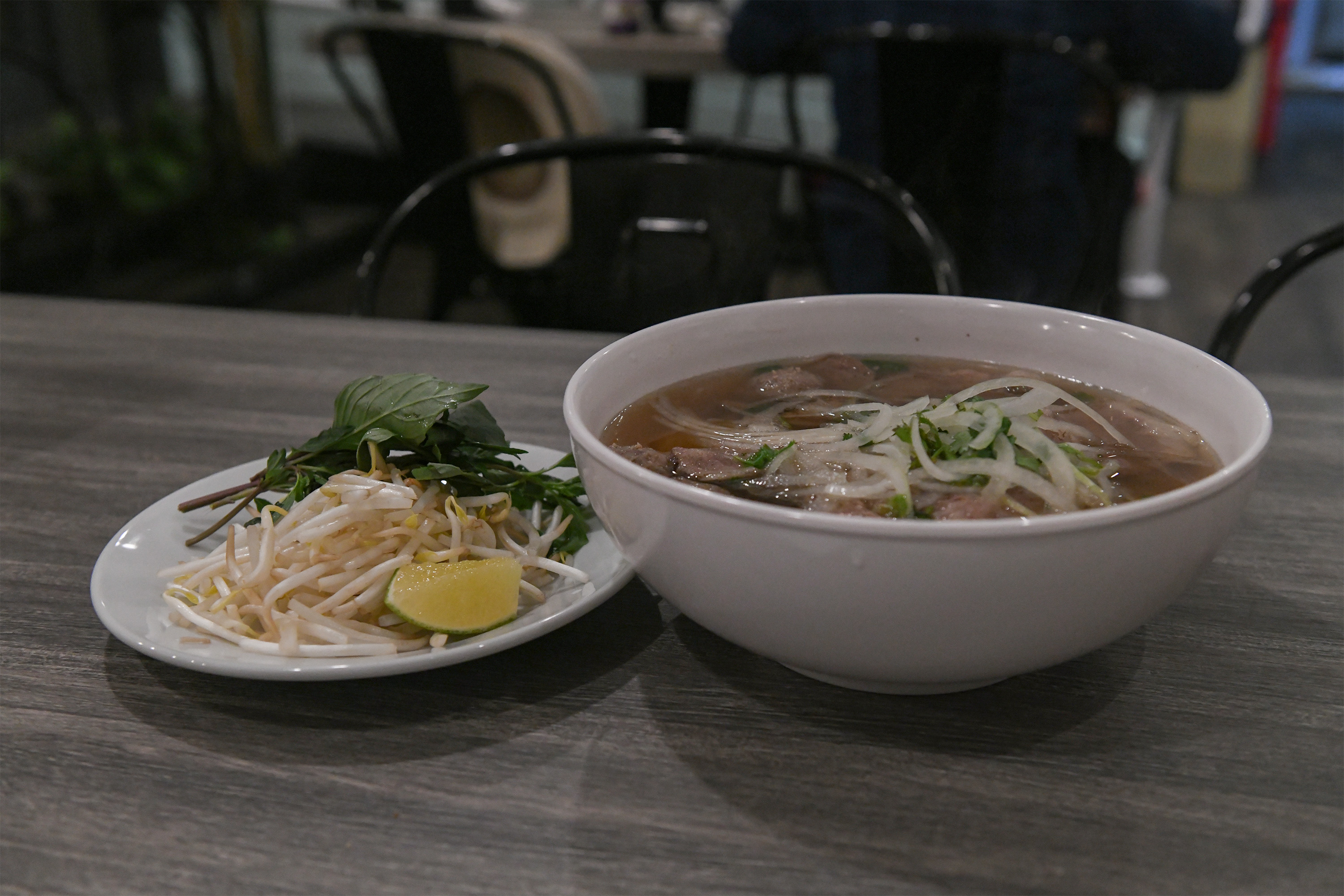 The beef ball and brisket pho from 26 Pho Cafe is pictured. The $16.99 dish comes with a plate of bean sprouts, lime and Thai basil. (Amelia Chief/Daily Bruin senior staff)