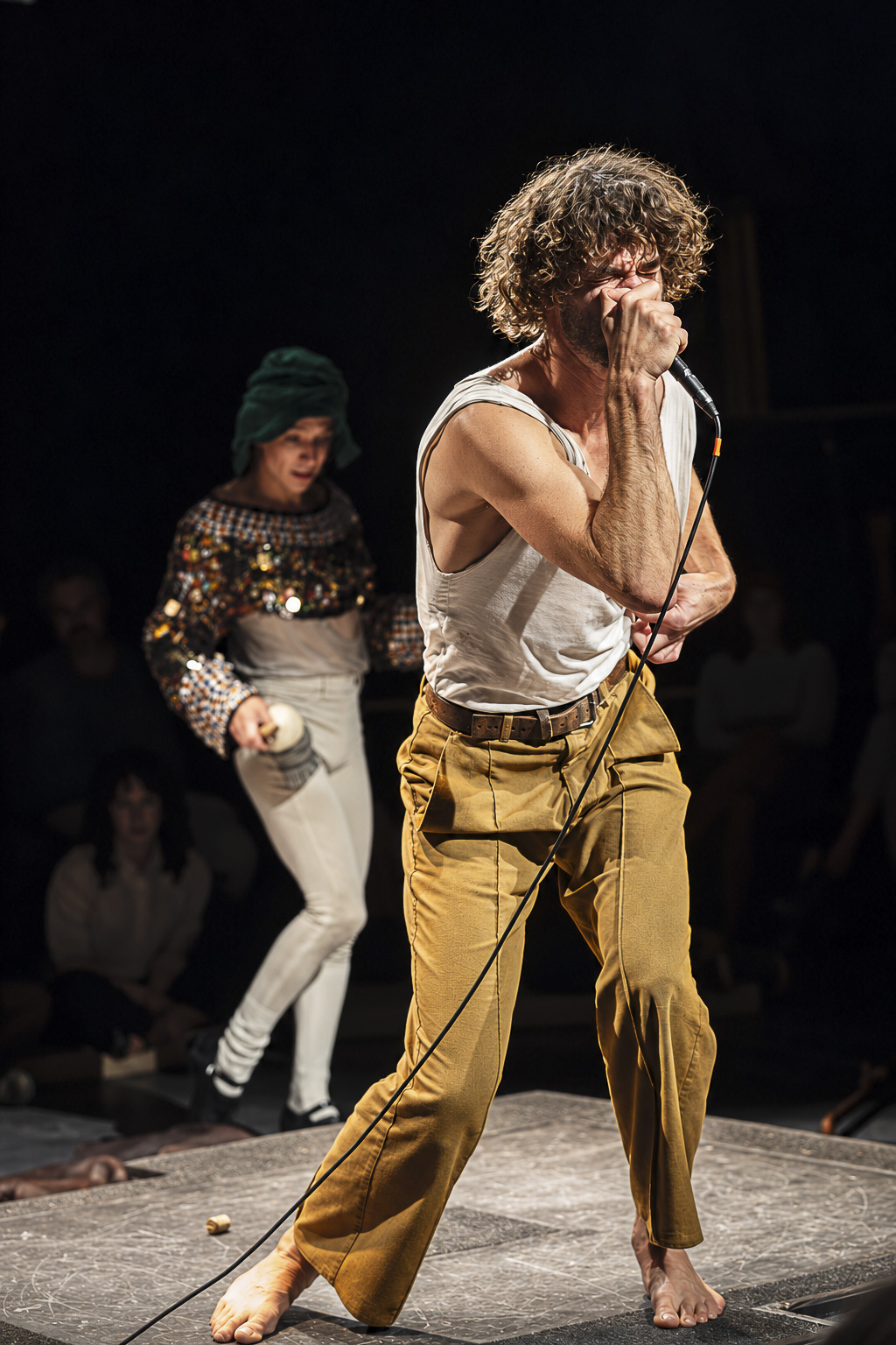 Hainaux holds a microphone, wearing brown pants and a white tank top. He began his artistic career with comics and painting before turning to beatboxing, emphasizing silence and movement, with sounds performed live rather than stacked through a loop pedal. (Courtesy of Chanel Foster)