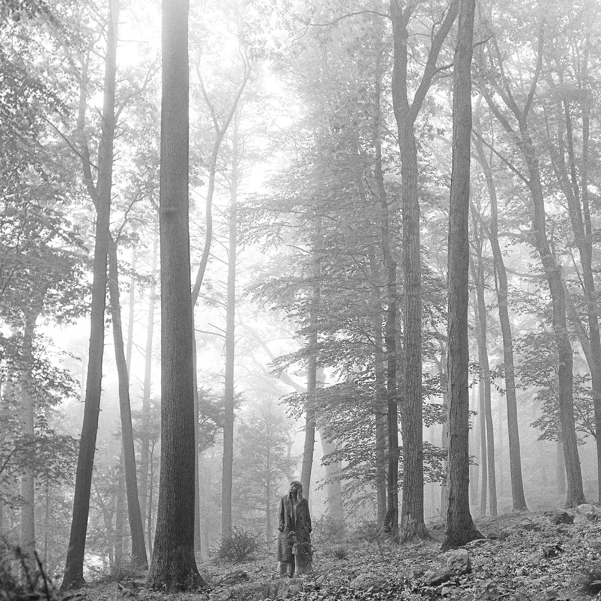 Set to a foggy, grayscale color palette, Swift looks upward in a forest surrounded by tall trees on the cover of “folklore,” released in July 2020. (Courtesy of 2020 Taylor Swift)