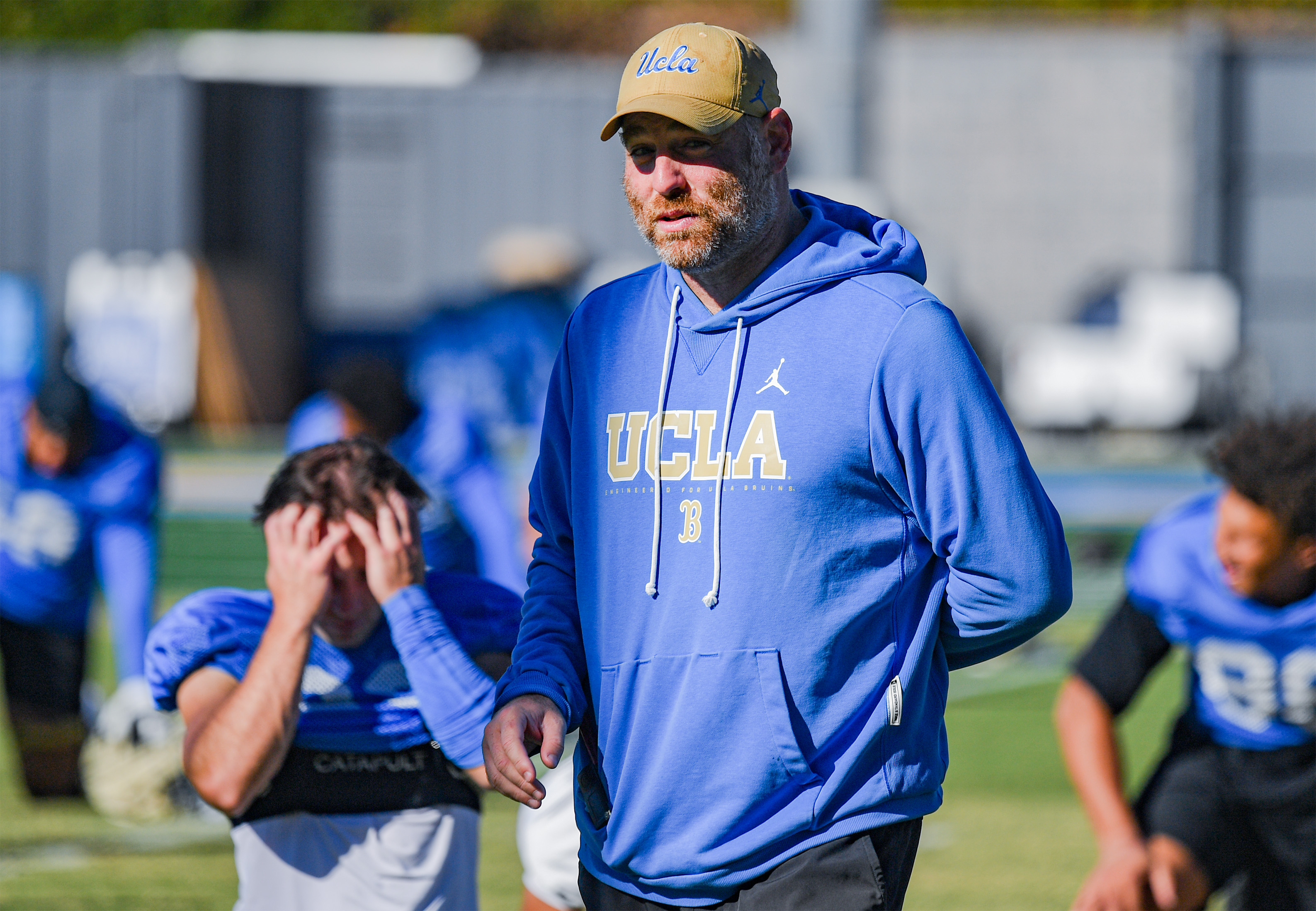 Defensive coordinator Colin Hitschler greets players as they stretch during practice Wednesday. (Kai Dizon/Assistant Photo editor)