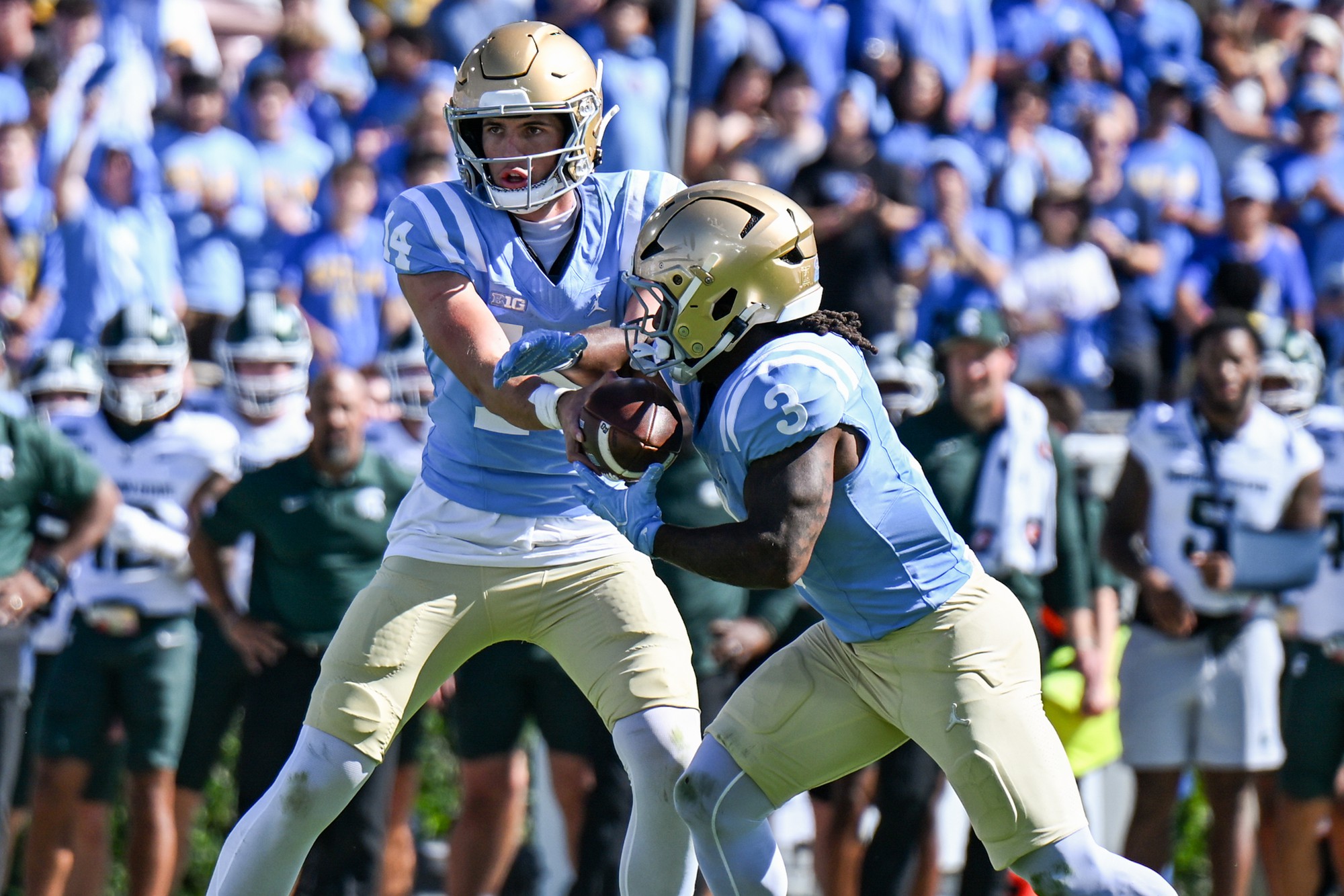 Senior quarterback Ty Dieffenbach (left) hands the ball off to fifth-year running back Wayne Knight (right) during UCLA’s game against Michigan State. Knight leads the Bruins with 12 rushing touchdowns this year. (Andrew Ramiro Diaz/Photo editor)