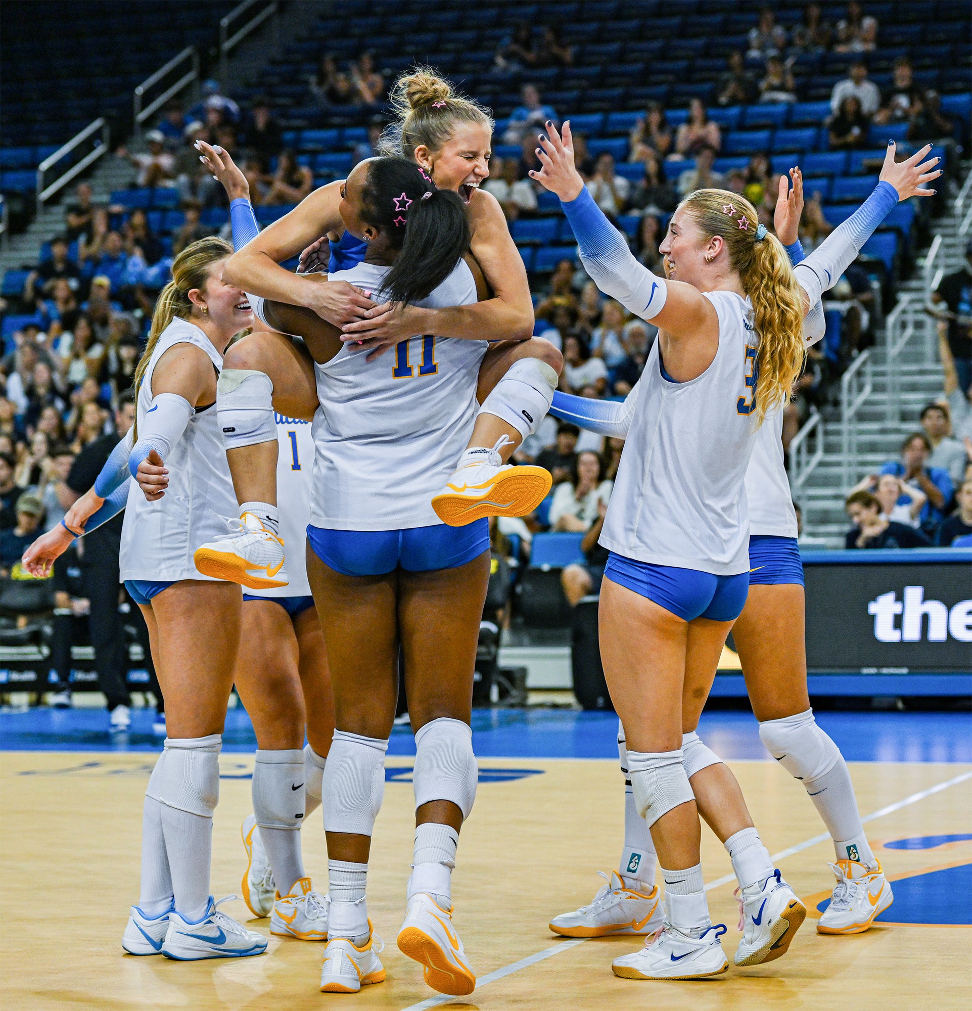 Junior libero Lola Schumacher leaps into the arms of fifth-year middle blocker Marianna Singletary. Schumacher left Friday night's match injured, resulting in senior libero Kat Lutz's first start of the season. (Presley Liu/Daily Bruin senior staff)